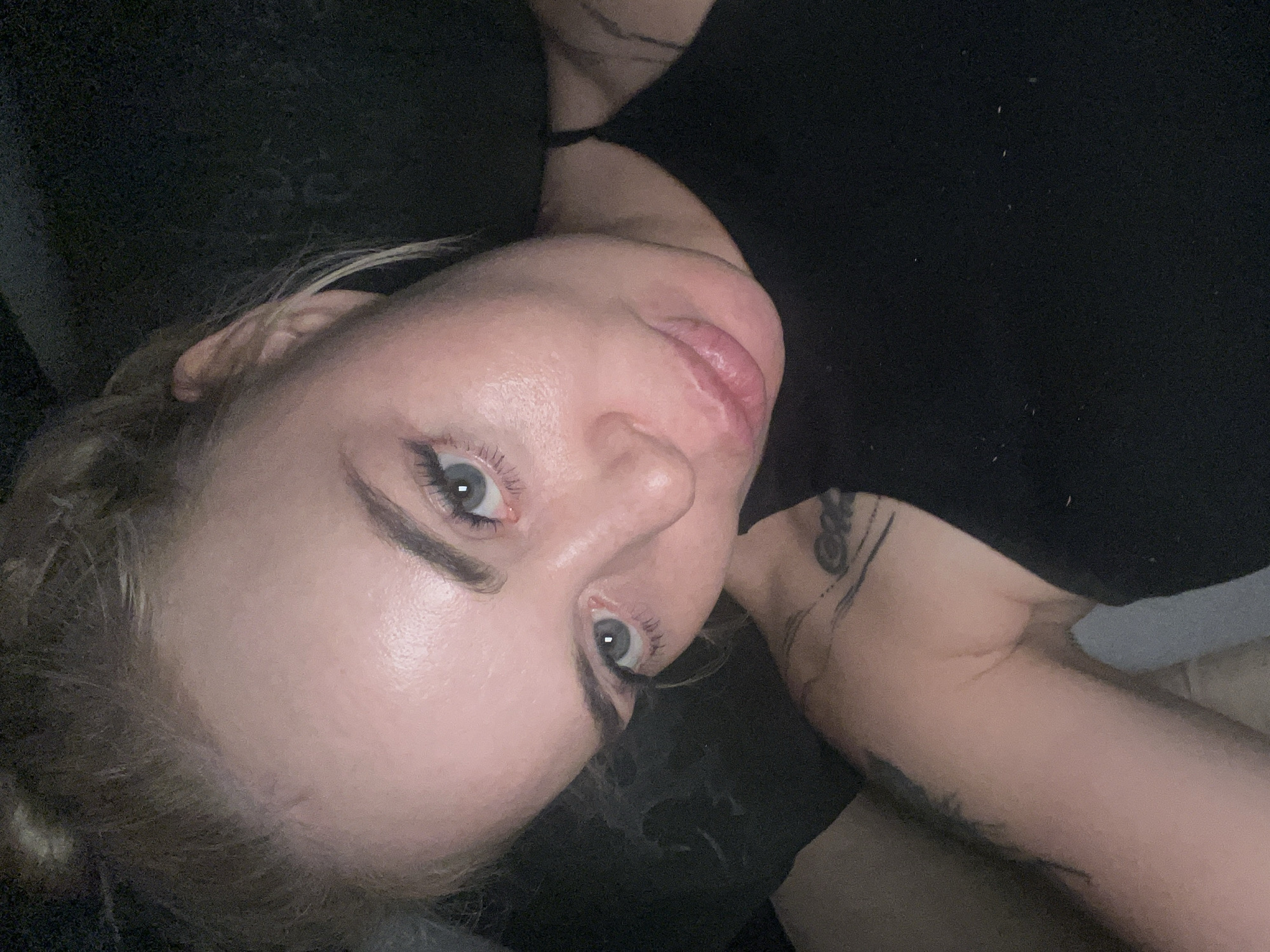 Close-up selfie session, lying down, dim indoor setting