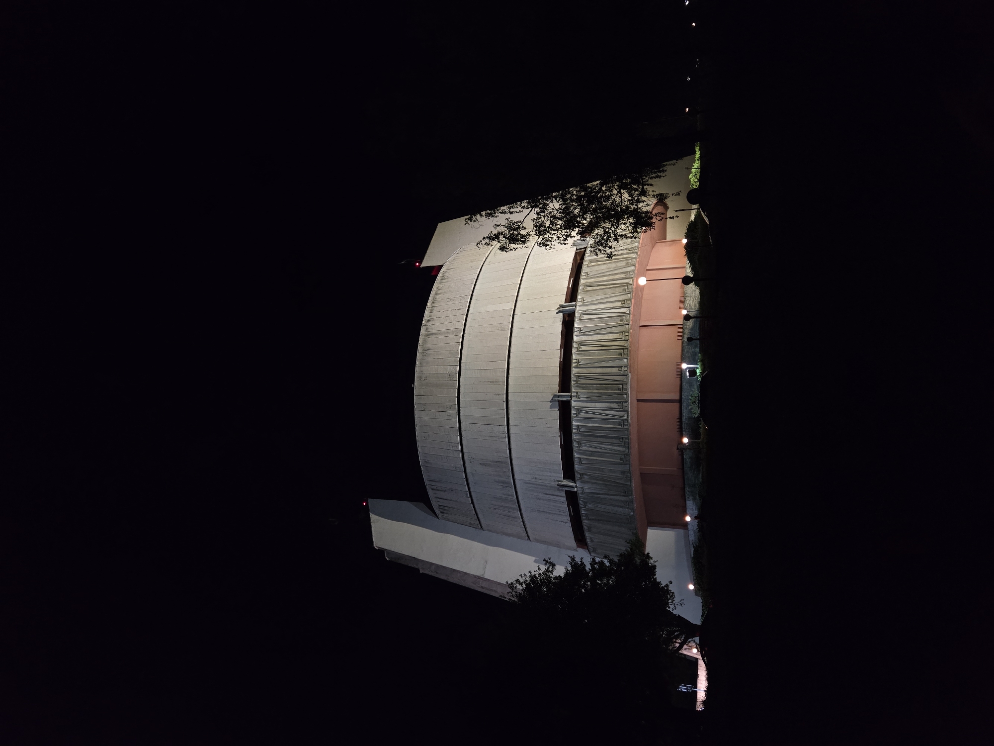Nighttime architectural structure photographed near parked vehicle