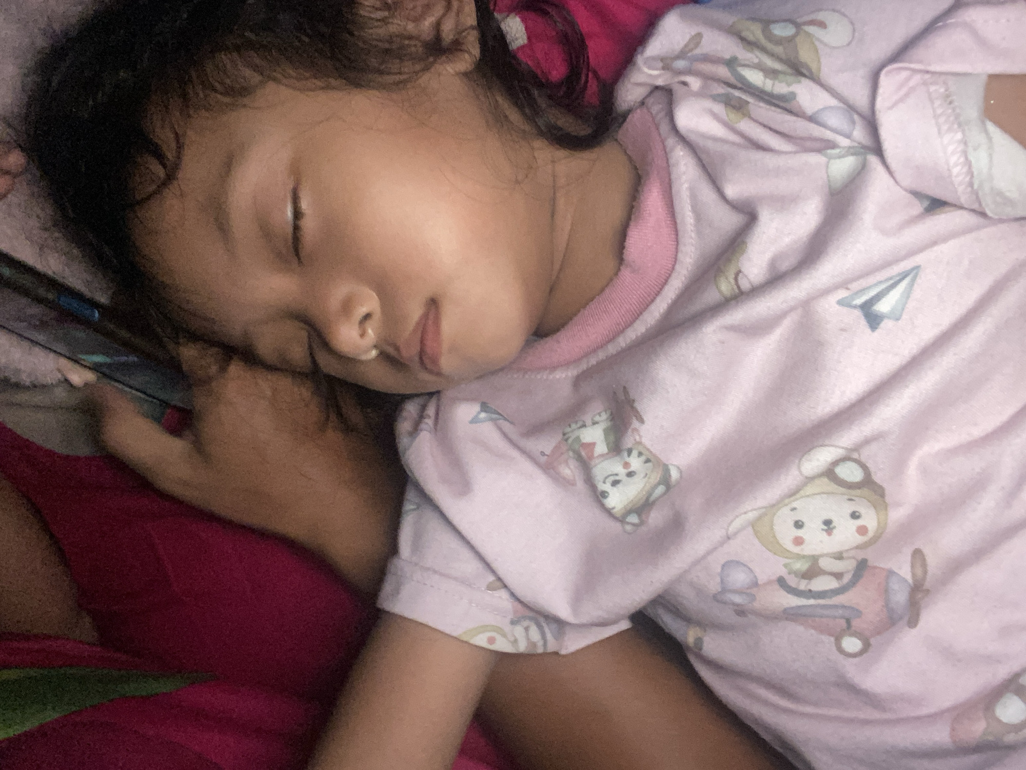 Child sleeps peacefully in pink cartoon top, Gelam