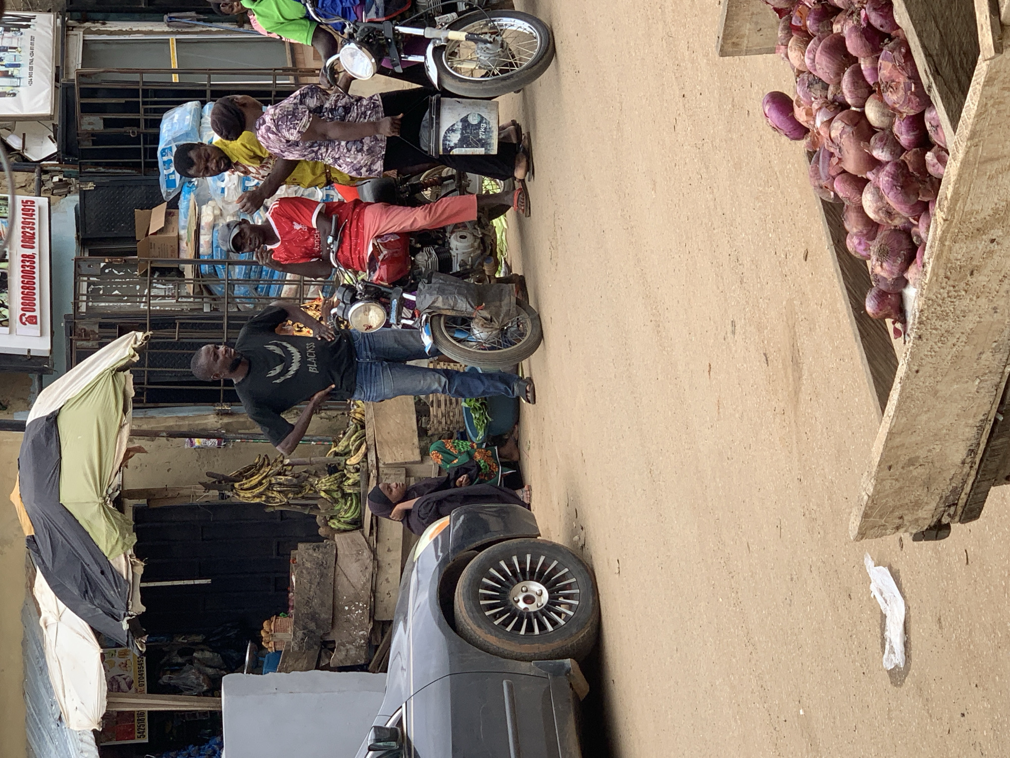 Abuja street market buzzing with vendors, pedestrians, and motos
