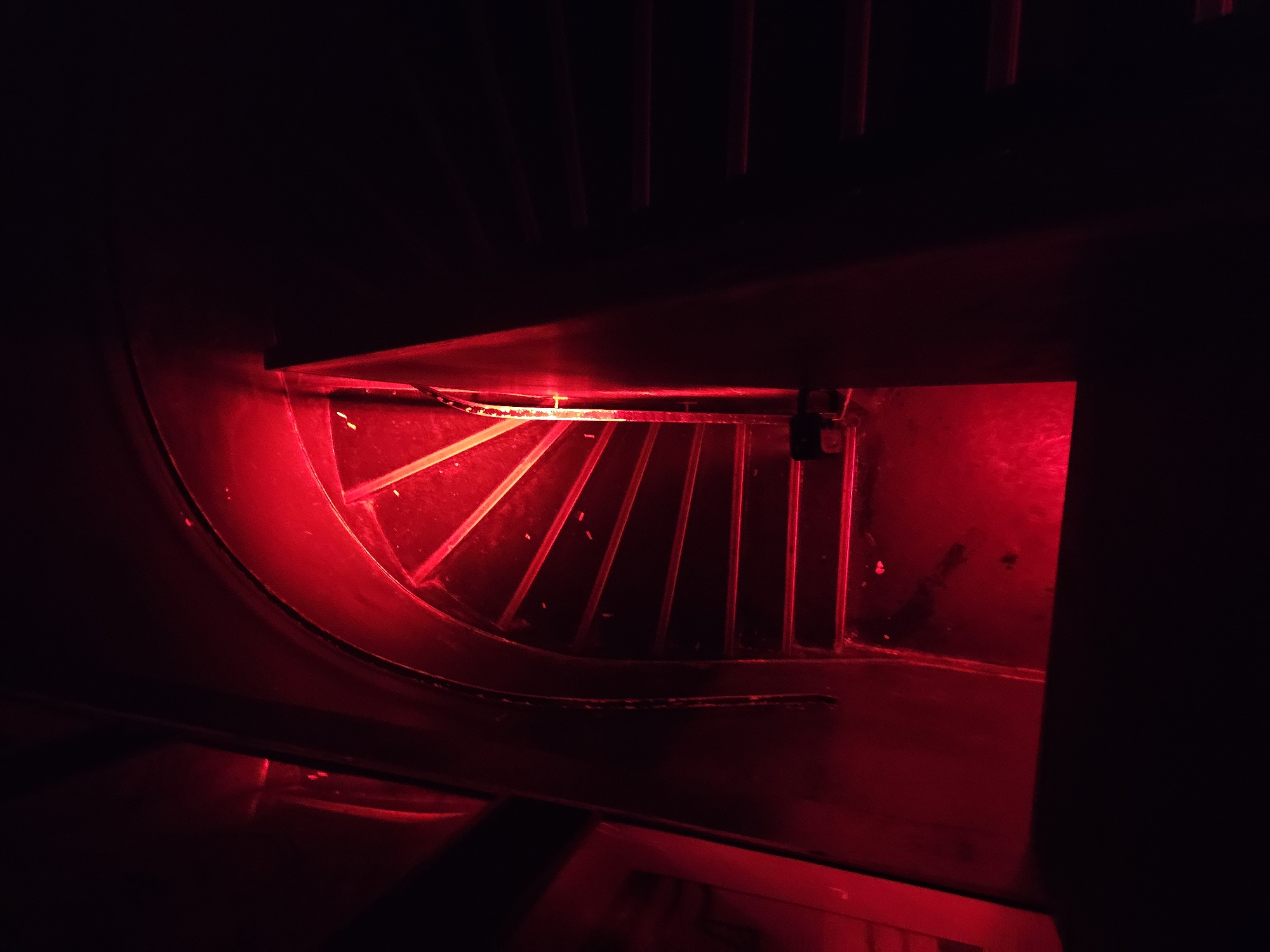 Red-lit machinery grate observed at unknown location