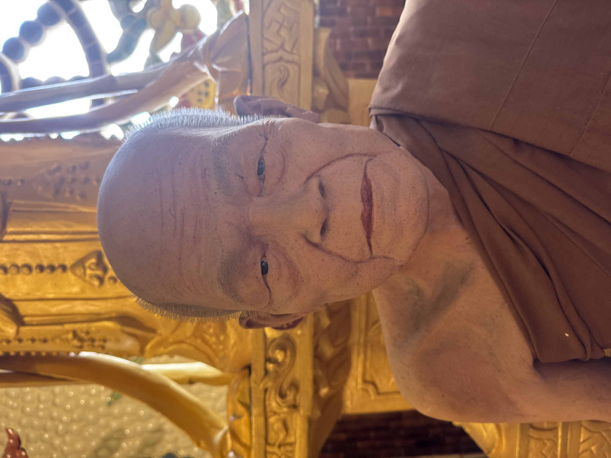 Hyperrealistic monk statues and golden deity shrine in Vietnamese temple