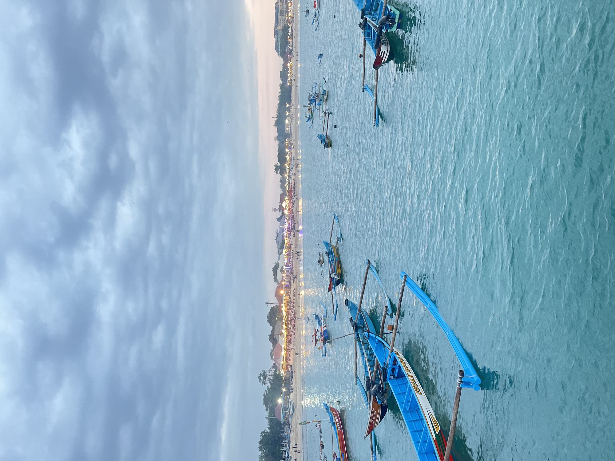 Kuta Beach at dawn — fishing boats, overcast skies, quiet waterfront