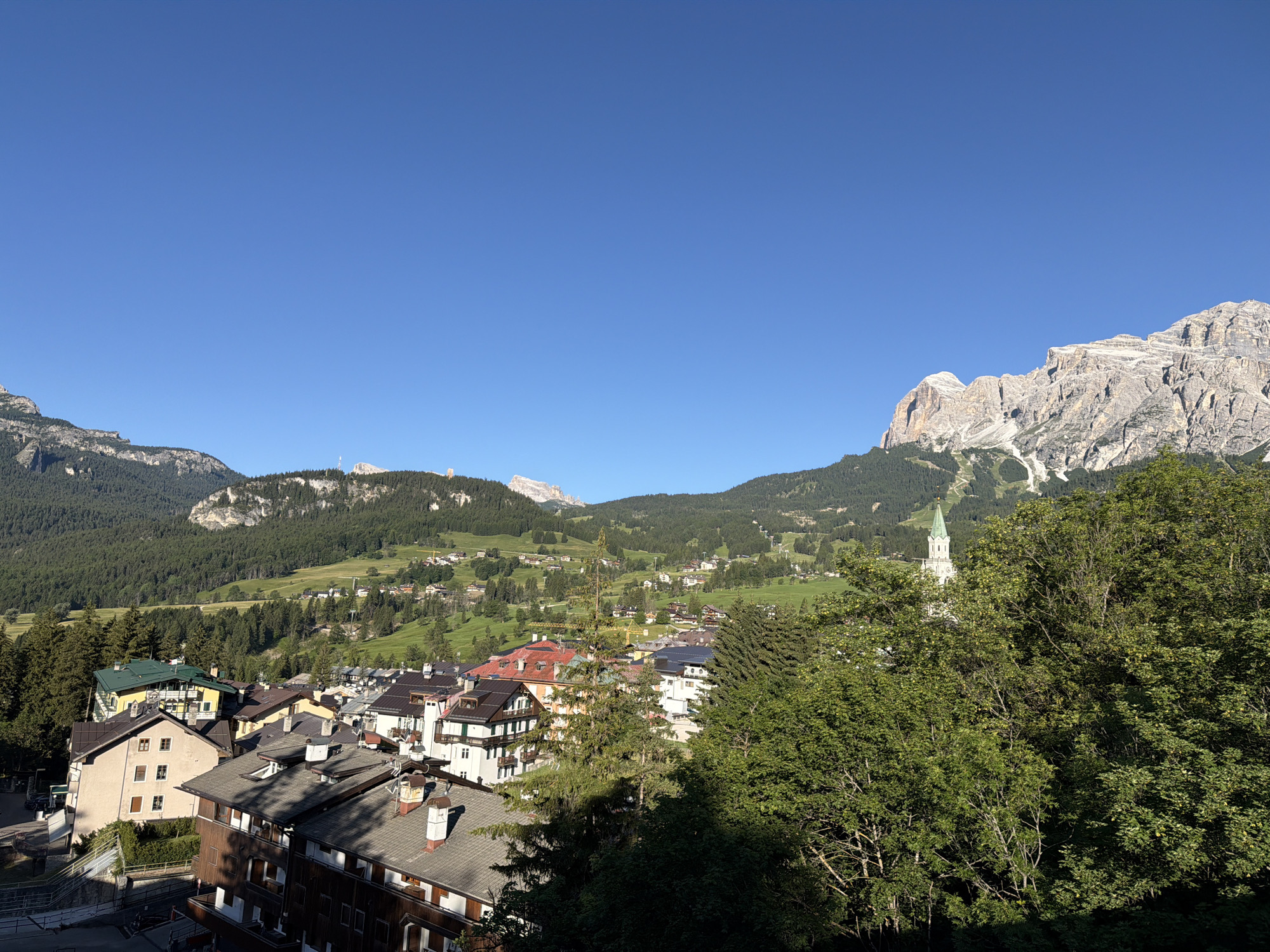Alpine valley town and mountain roads on a clear summer morning