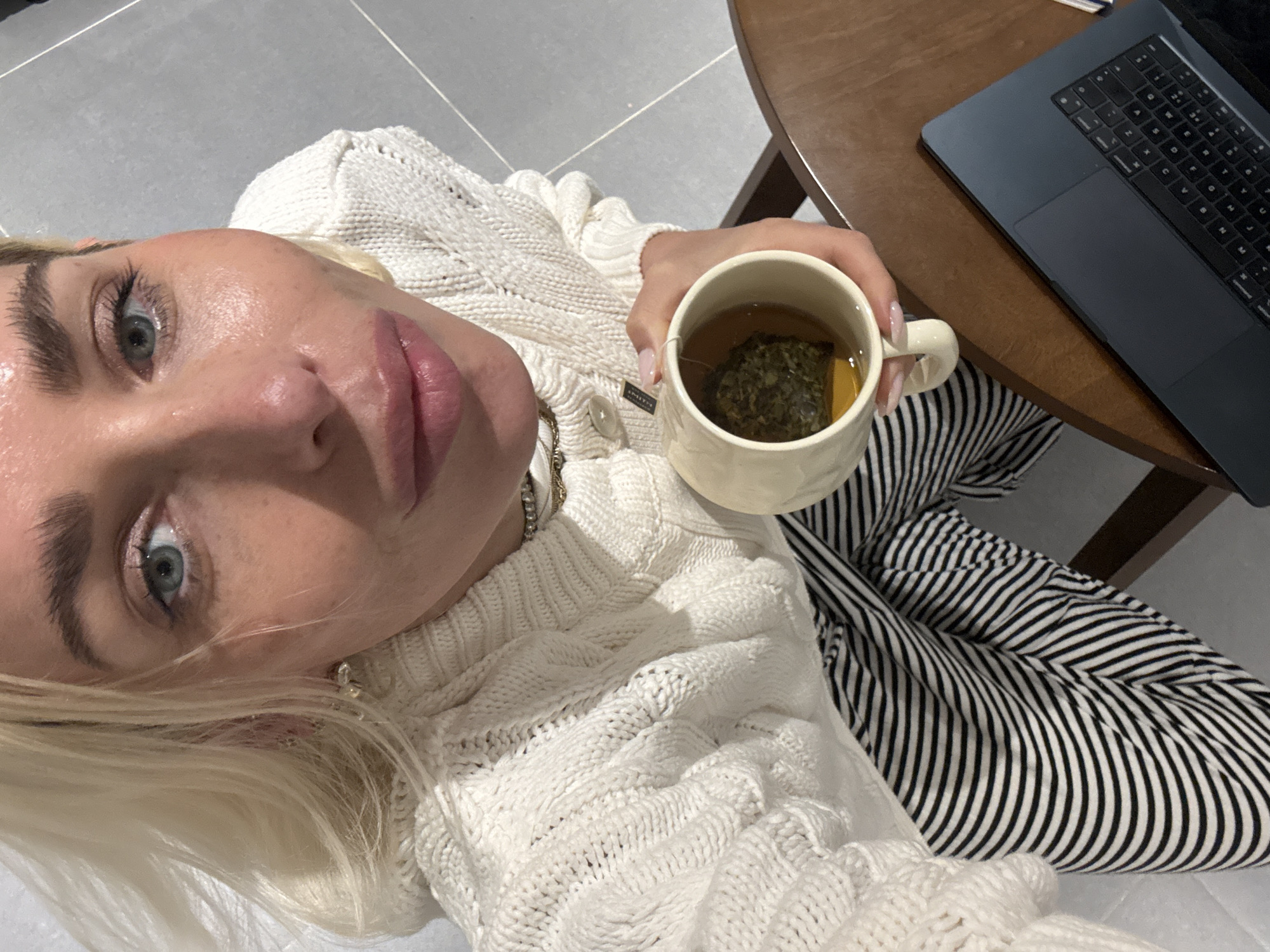 Person enjoys tea break with laptop in Dubai apartment