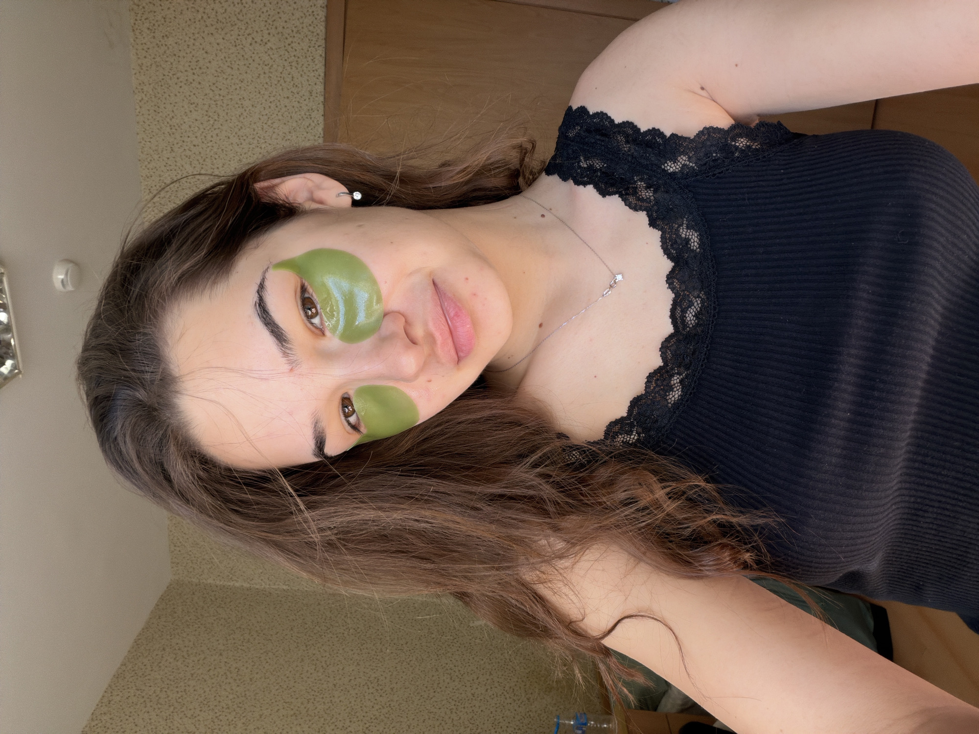 Woman applies green skincare patches during beauty routine in Sofia