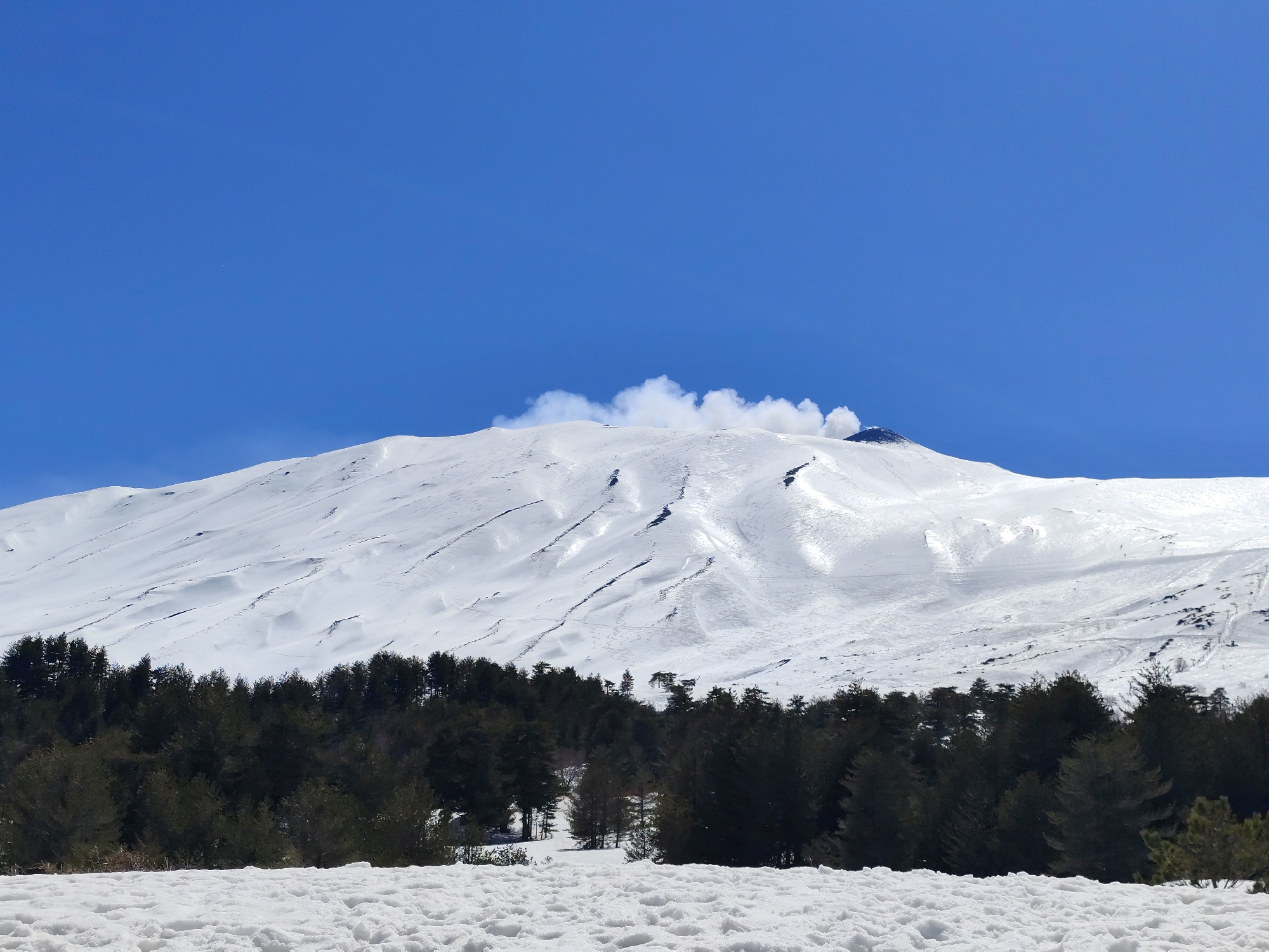 Mount Etna emits plumes amid spring snow near Linguaglossa