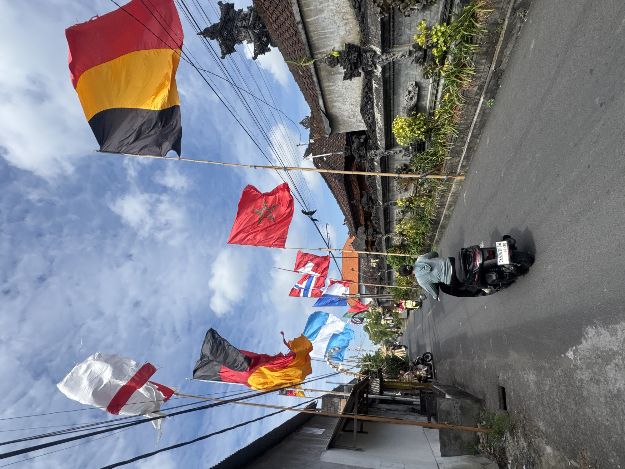Rows of international flags line a Kuta street on a cloudy day