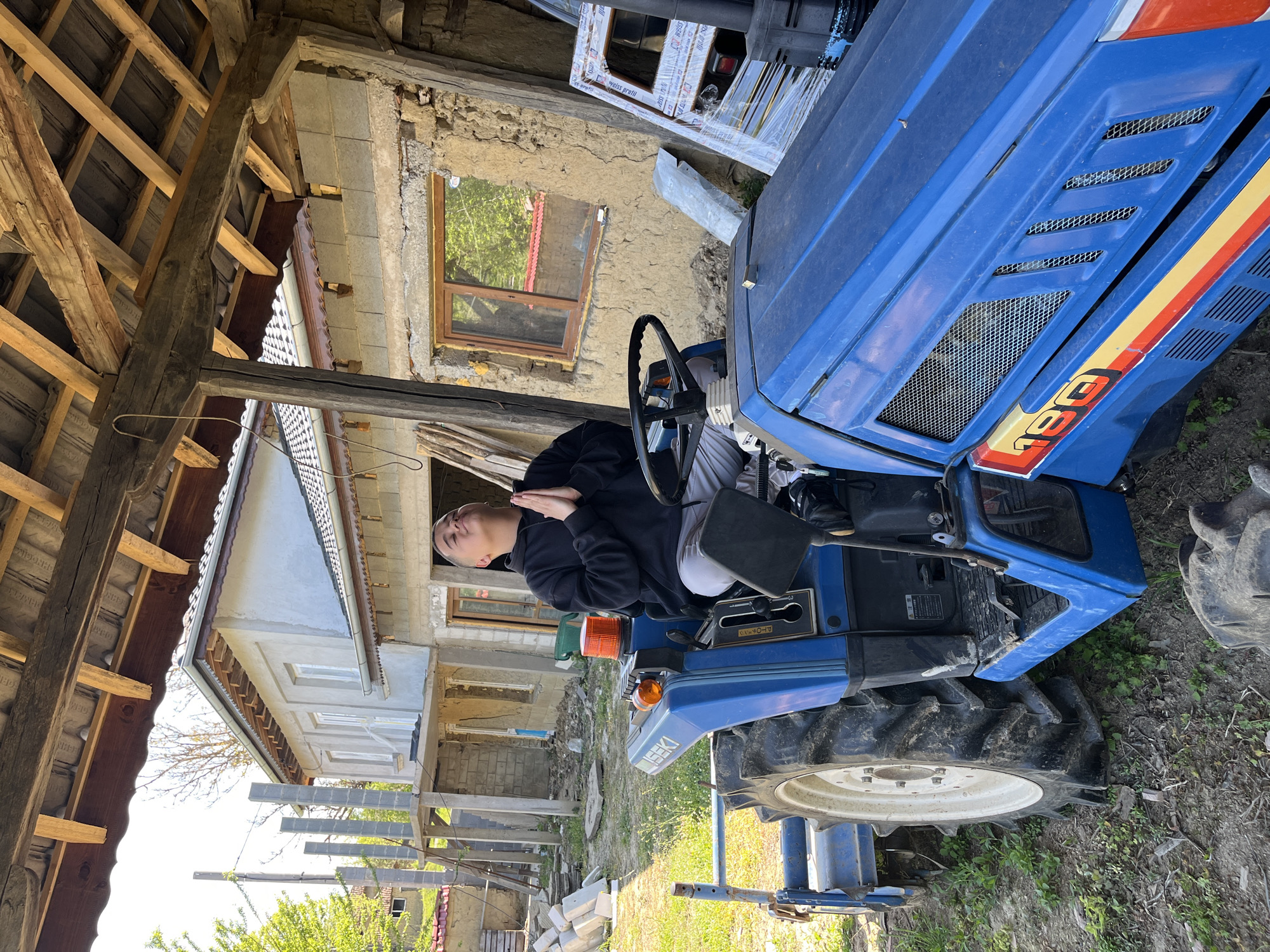 Person sits on blue tractor in rural Bulgaria