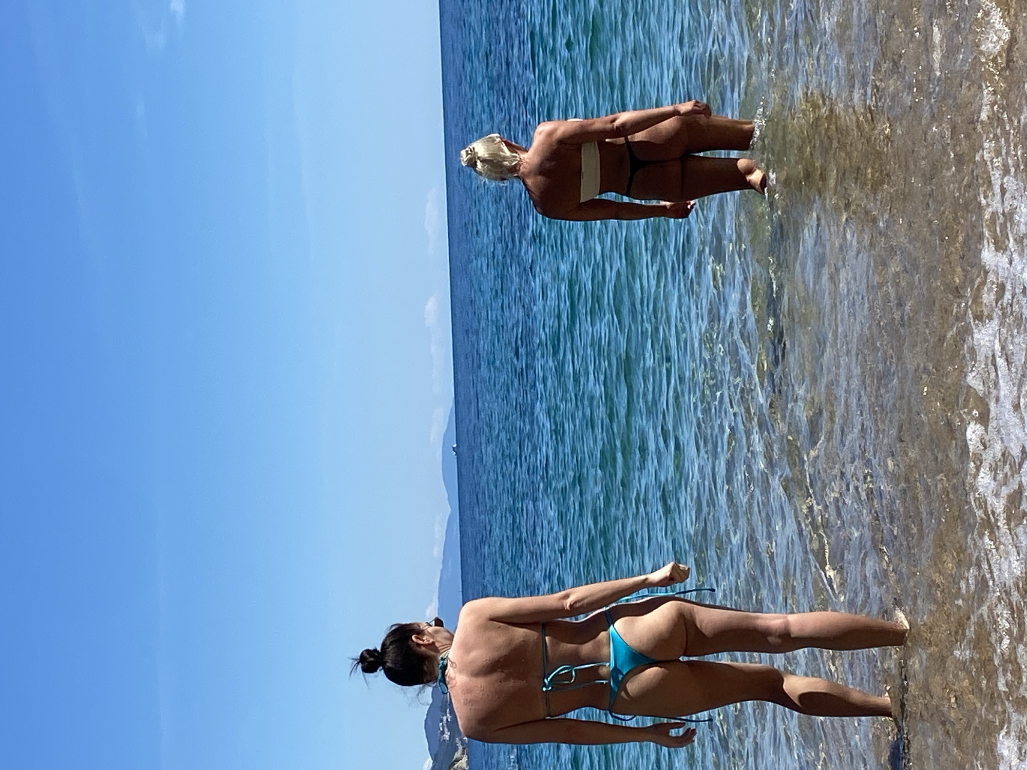 Two women wade in shallow water at Budva beach