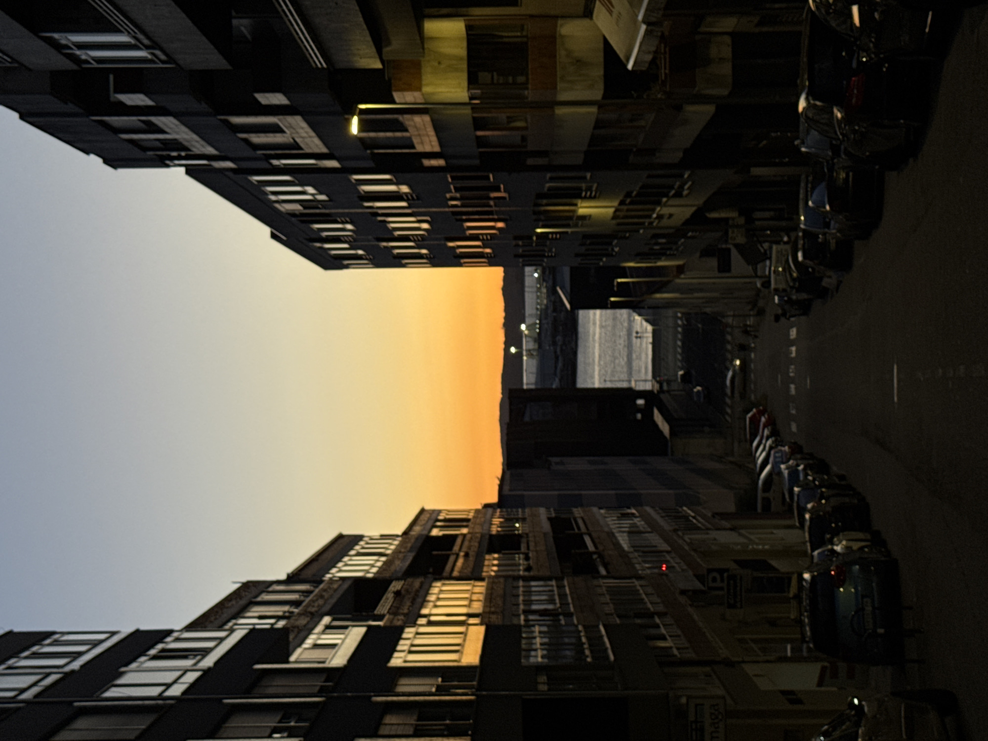 Vigo street at dusk, building windows glowing with sunset light