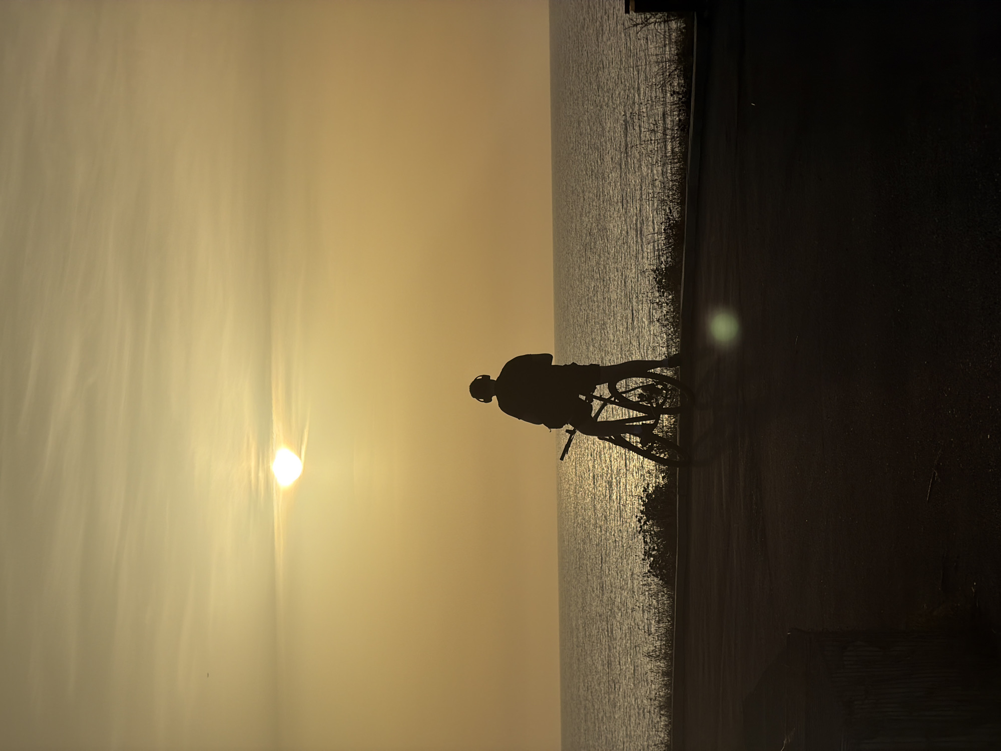 Cyclist silhouetted against sunset along Mediterranean coast in Bat Yam