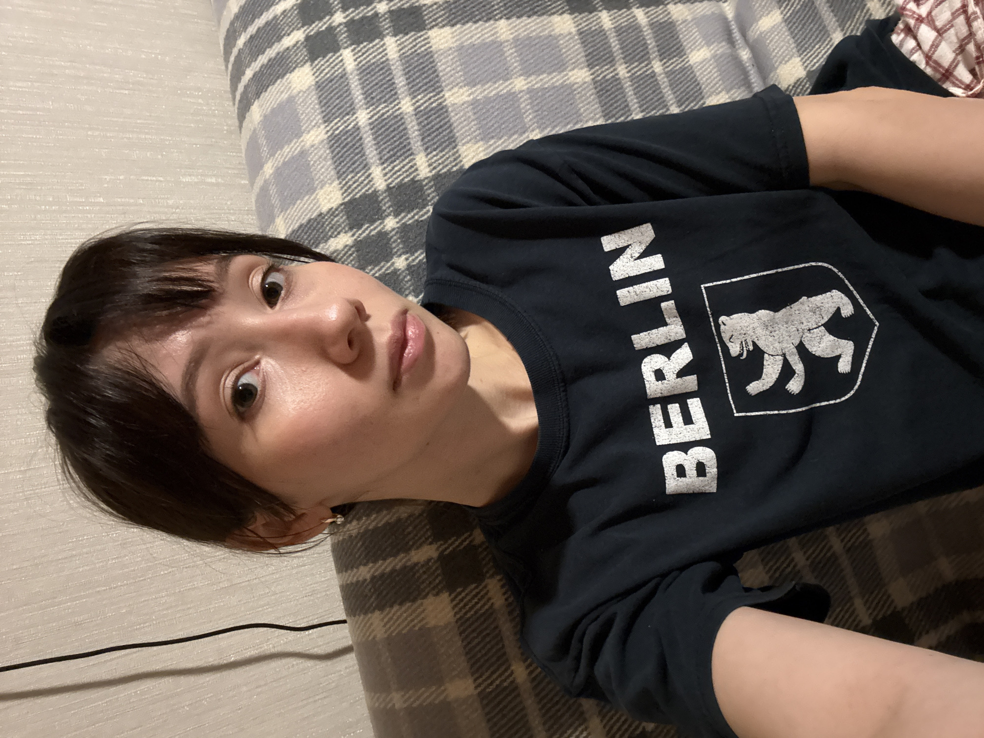 Woman in Berlin t-shirt resting on plaid surface in Kazan