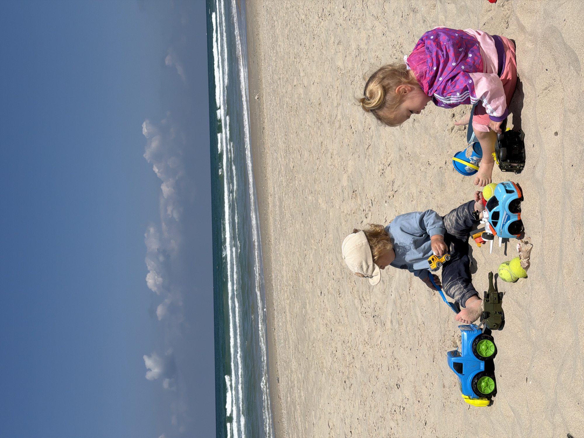 Children play with toys on sunny beach morning