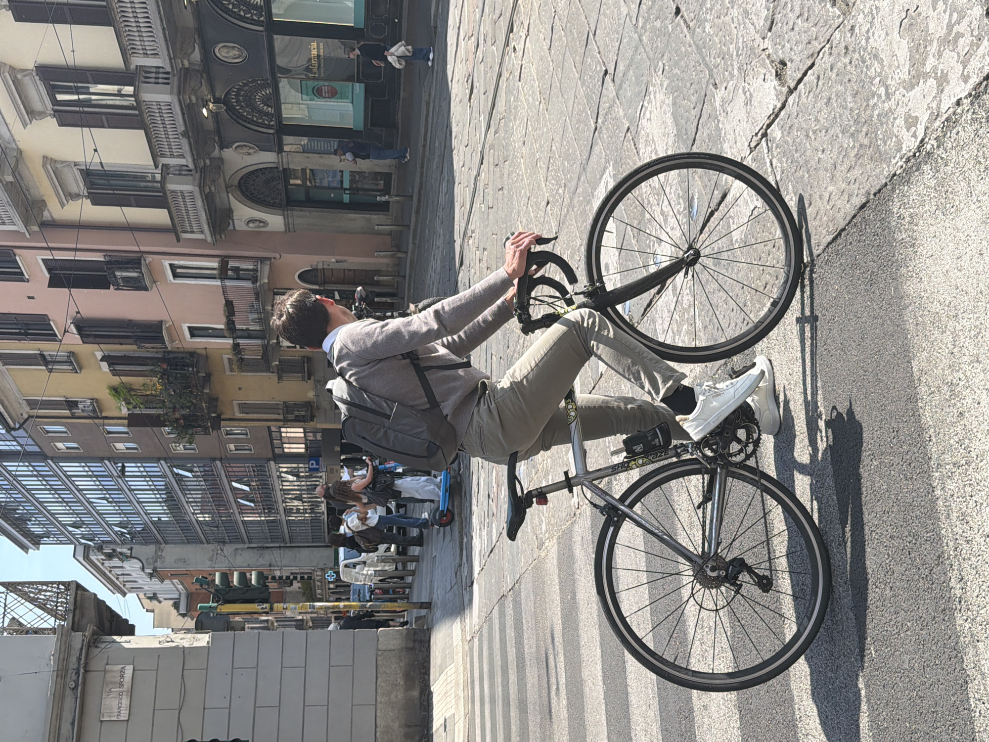 Cyclist spotted on sunlit Milan street amid spring foliage