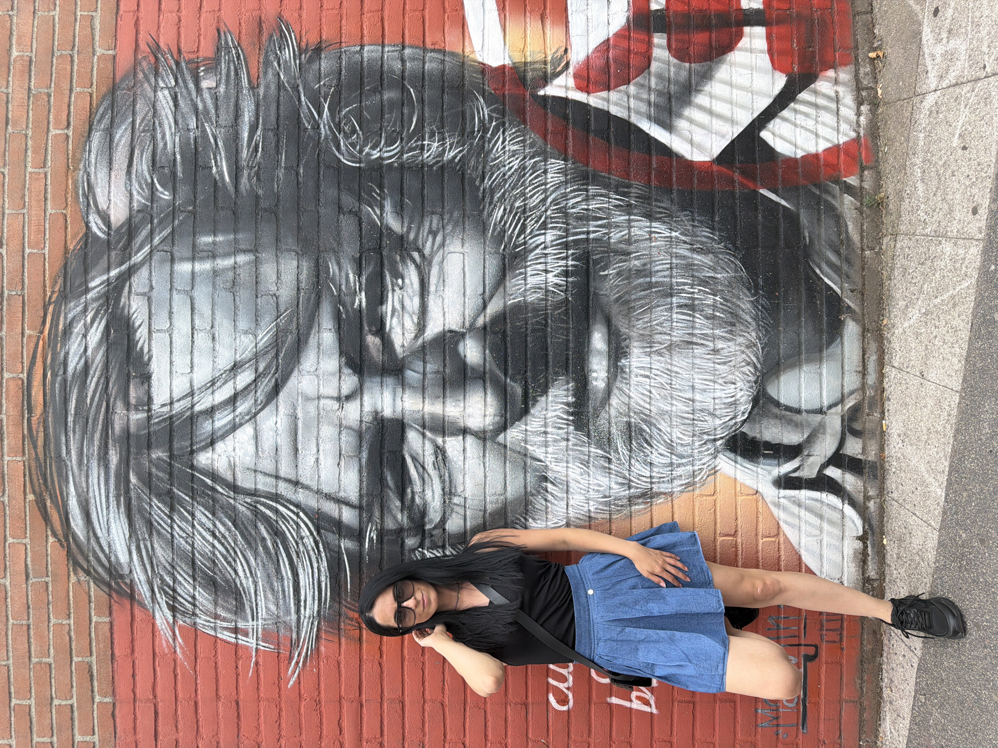 Posing with street art murals on a Corsico brick wall.