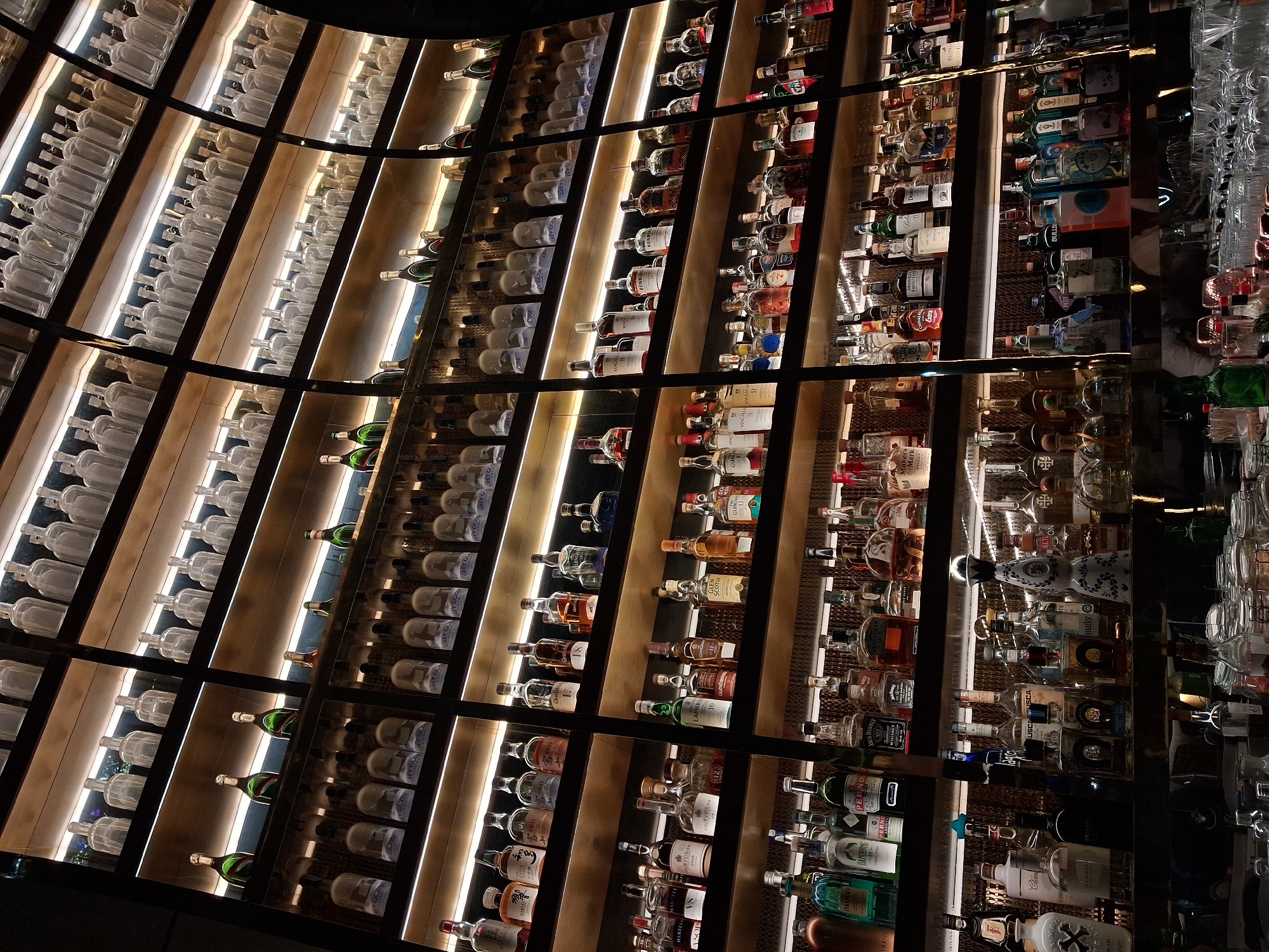 Bar establishment displays extensive liquor collection on illuminated shelves