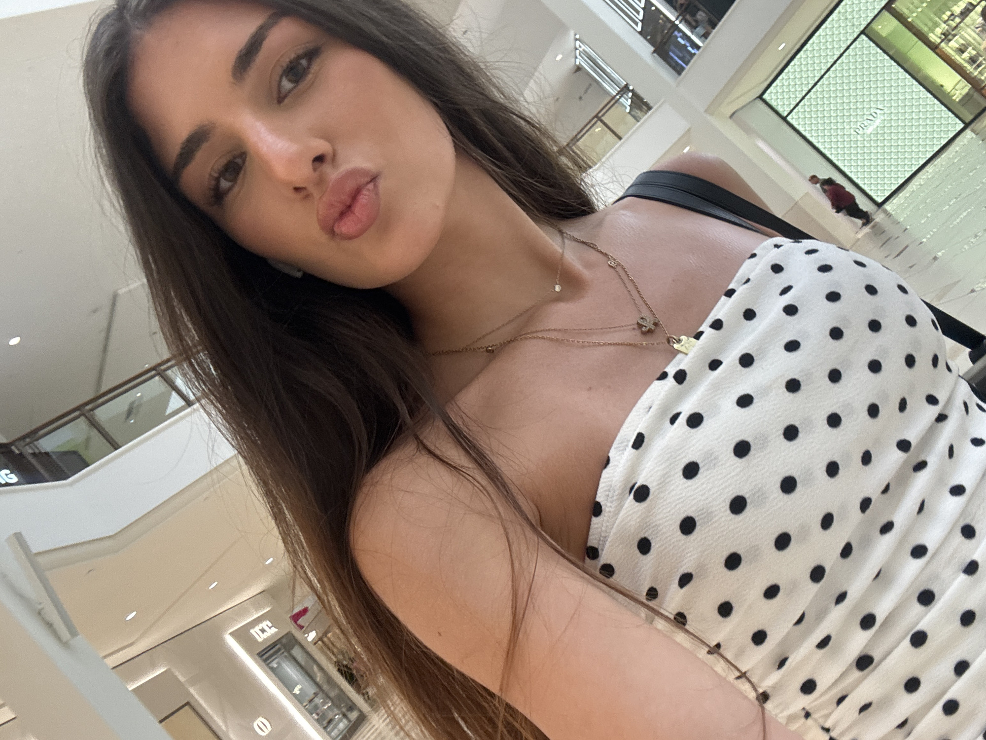 Selfies on a shopping mall escalator in a polka-dot top