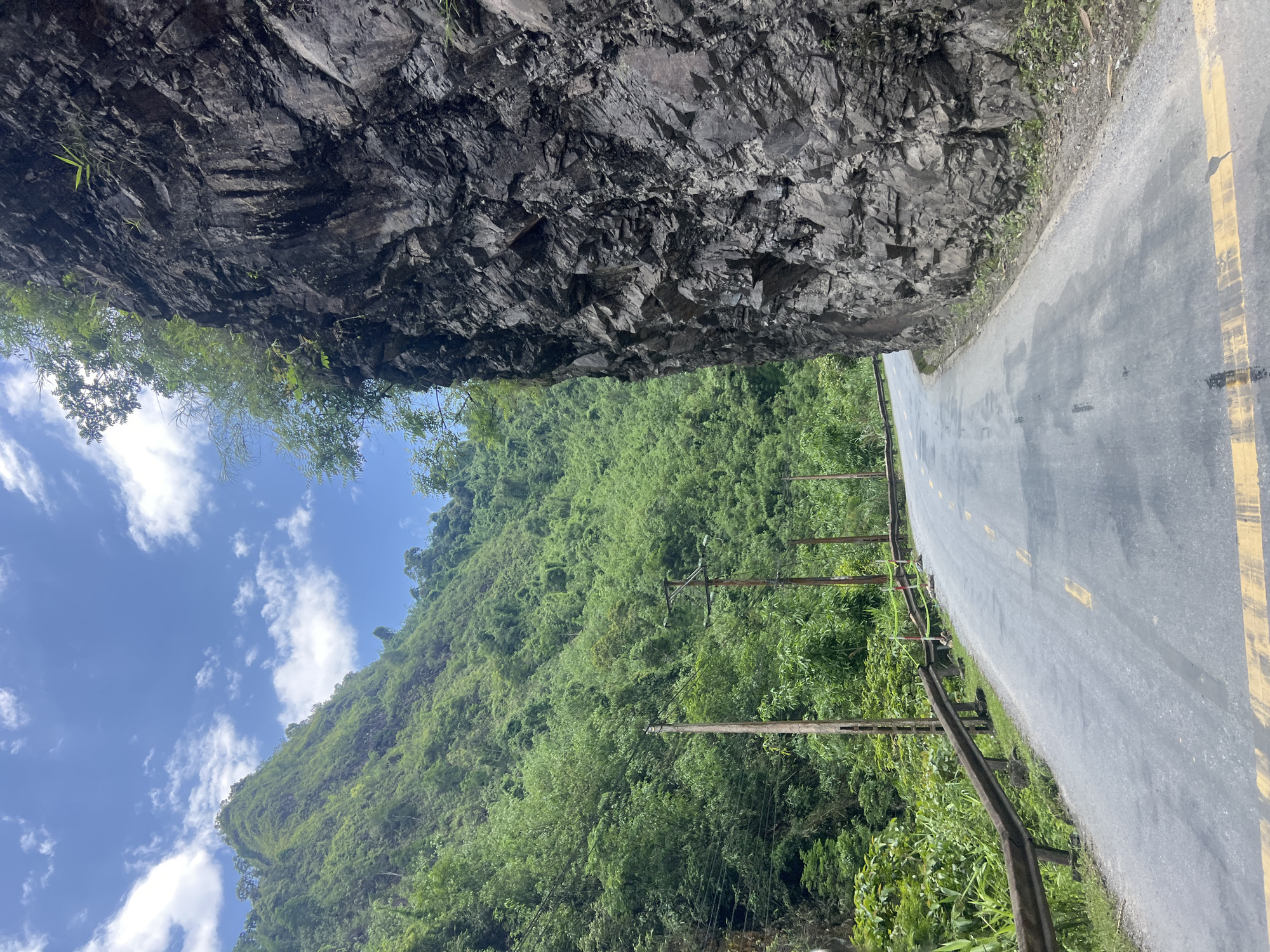 Winding mountain road through rocky cliffs and forest, Minh Tân