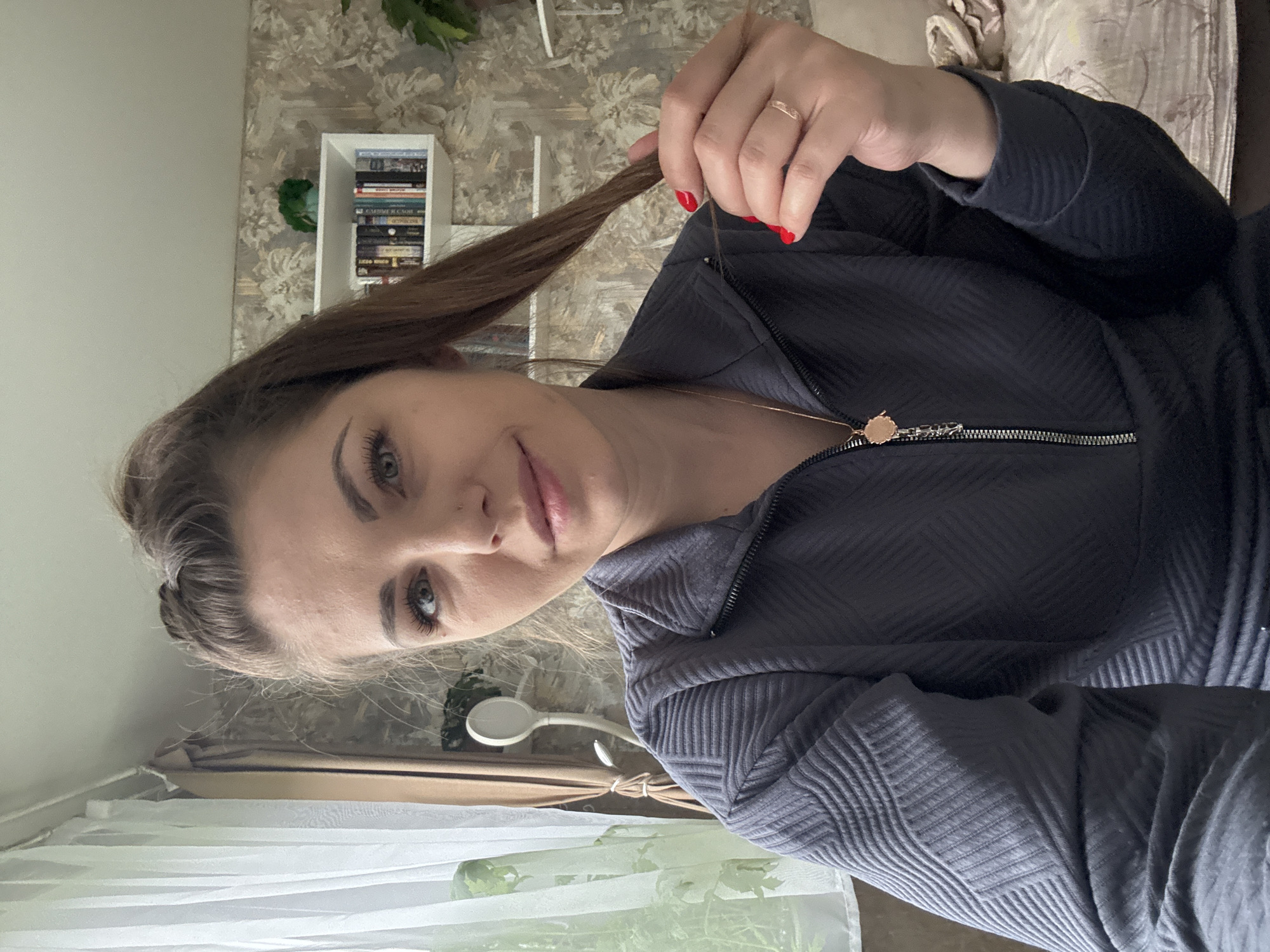 Woman holds hair strand indoors in Razdolye, Russia