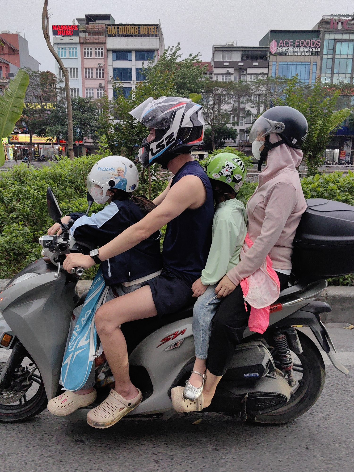 Helmet-wearing family of four shares single scooter in Hanoi