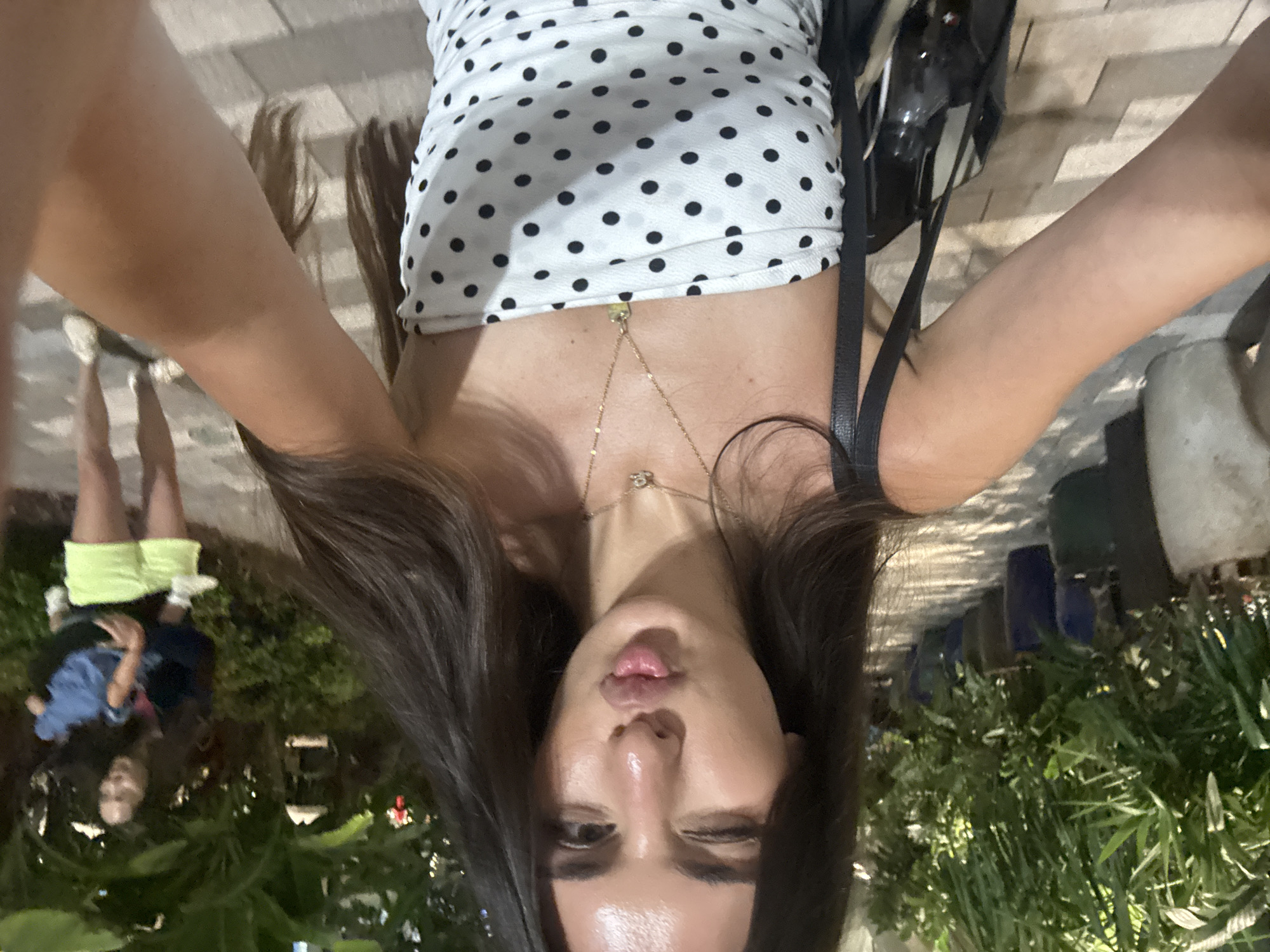 Polka-dot dress selfie session on a paved walkway at night