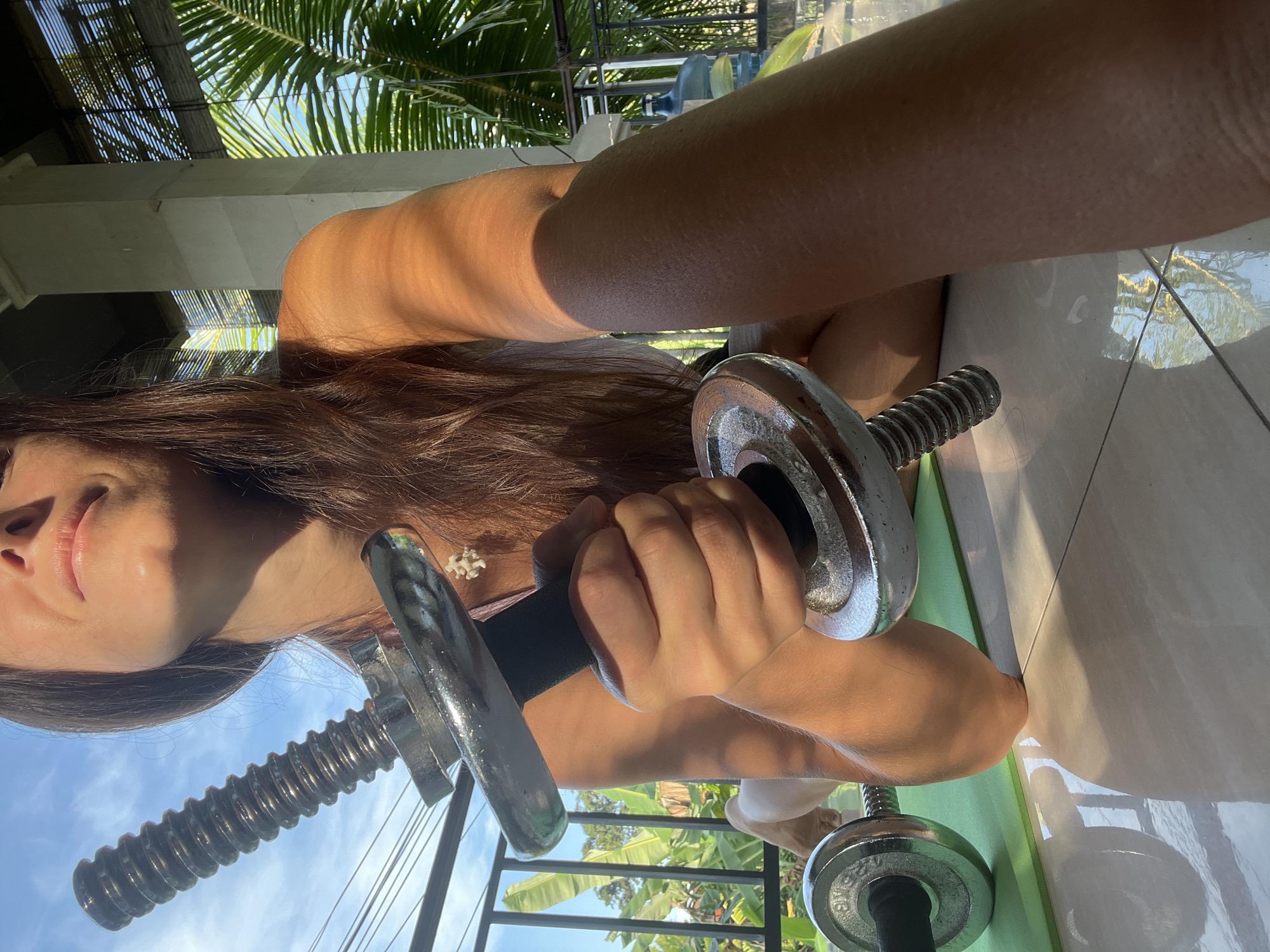 Woman exercises with dumbbells outdoors in Ubud, Indonesia