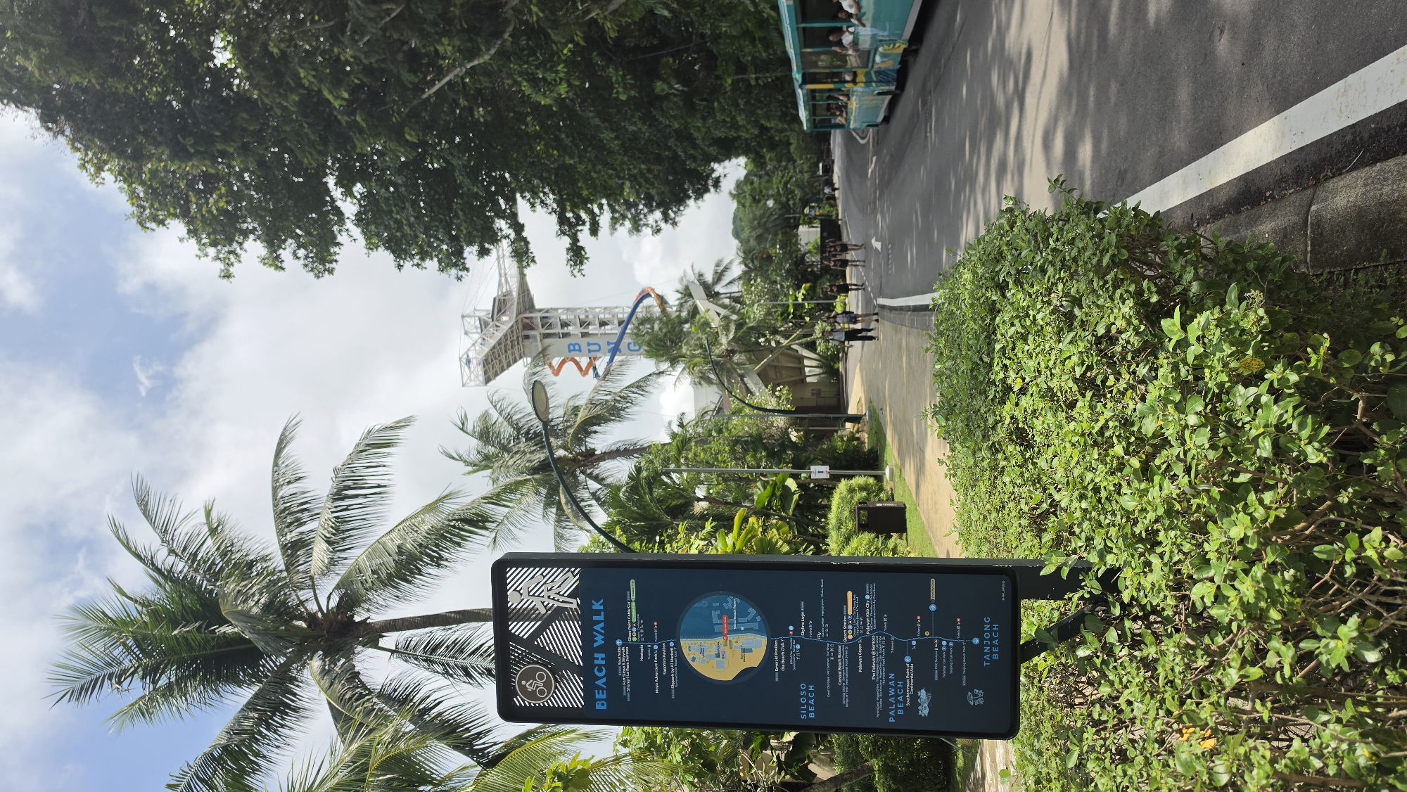 Singapore coastal park path with signage and greenery