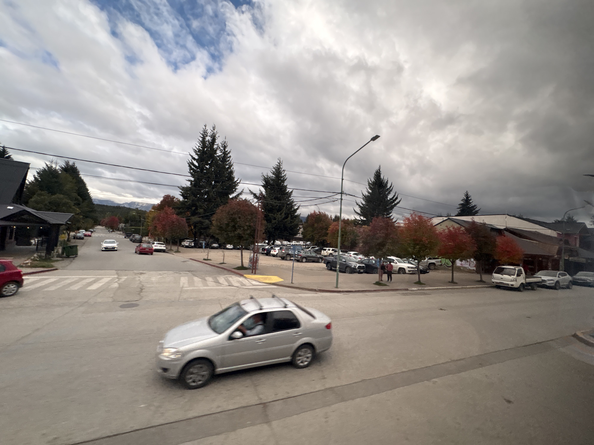Vehicle crosses intersection in Villa La Angostura under overcast sky
