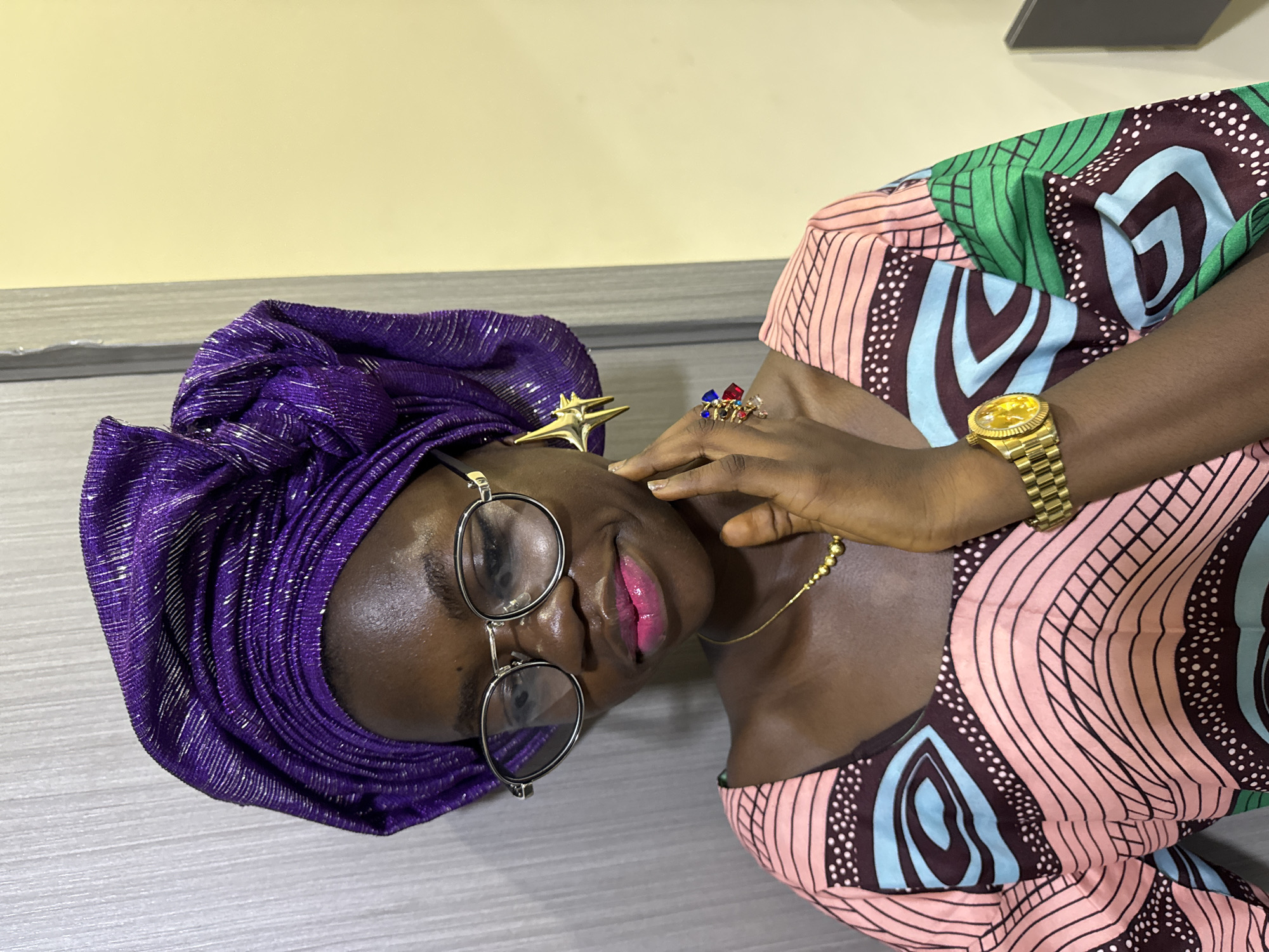 Woman in purple headwrap takes selfies, applies makeup in Nigeria