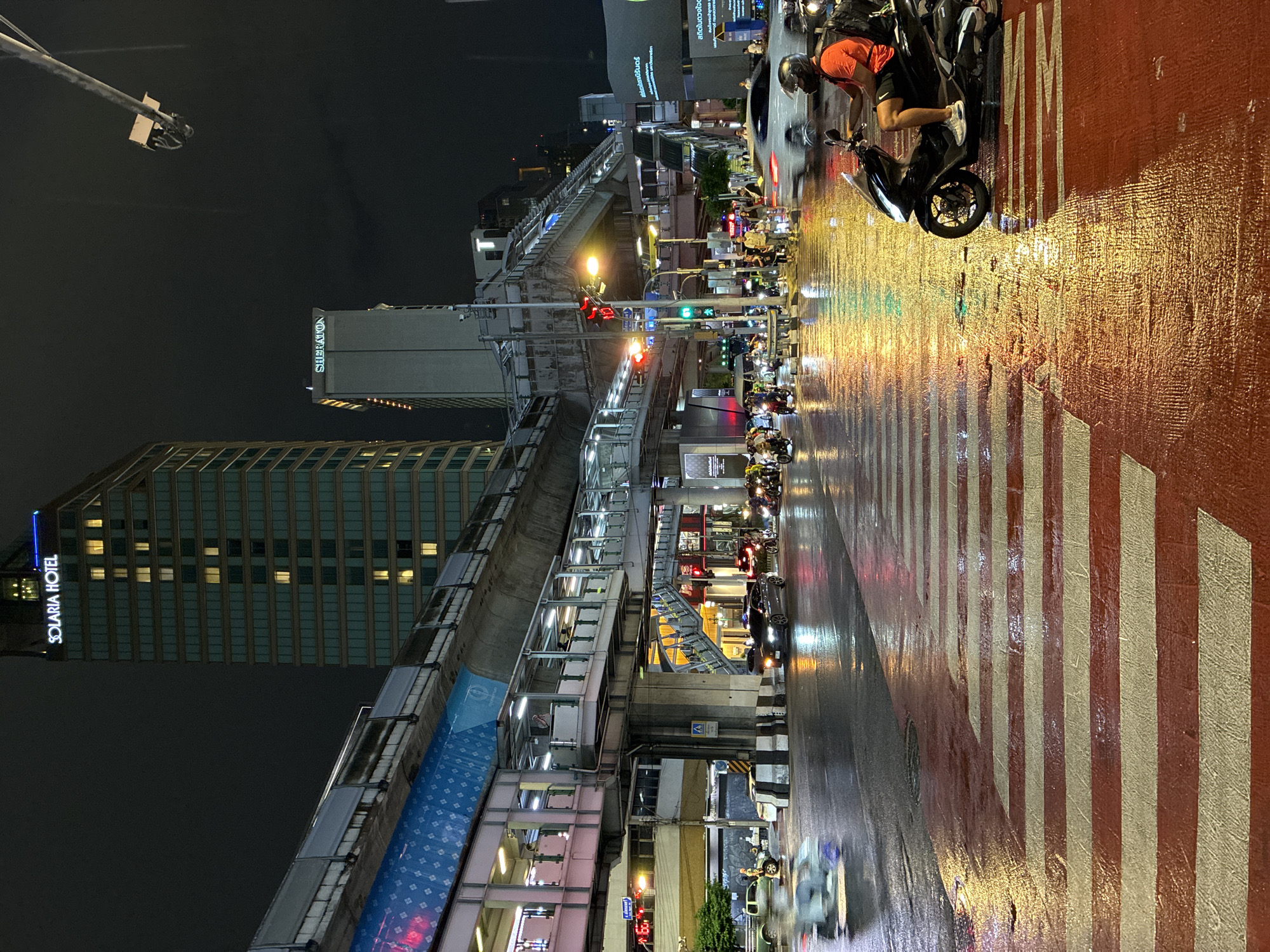 Rainy night reflections at a busy Bangkok intersection