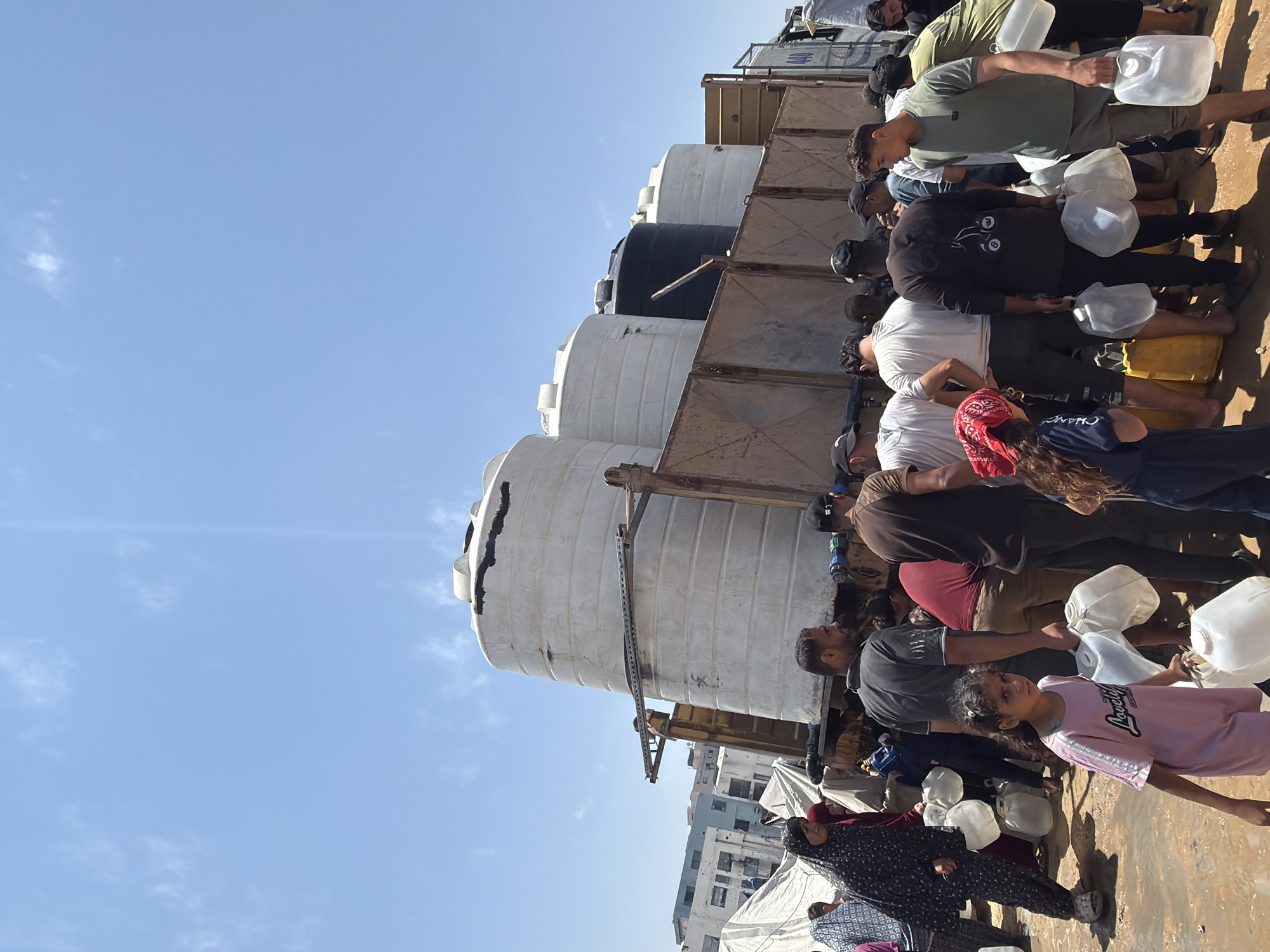 Gaza residents collect water from distribution truck amid displacement