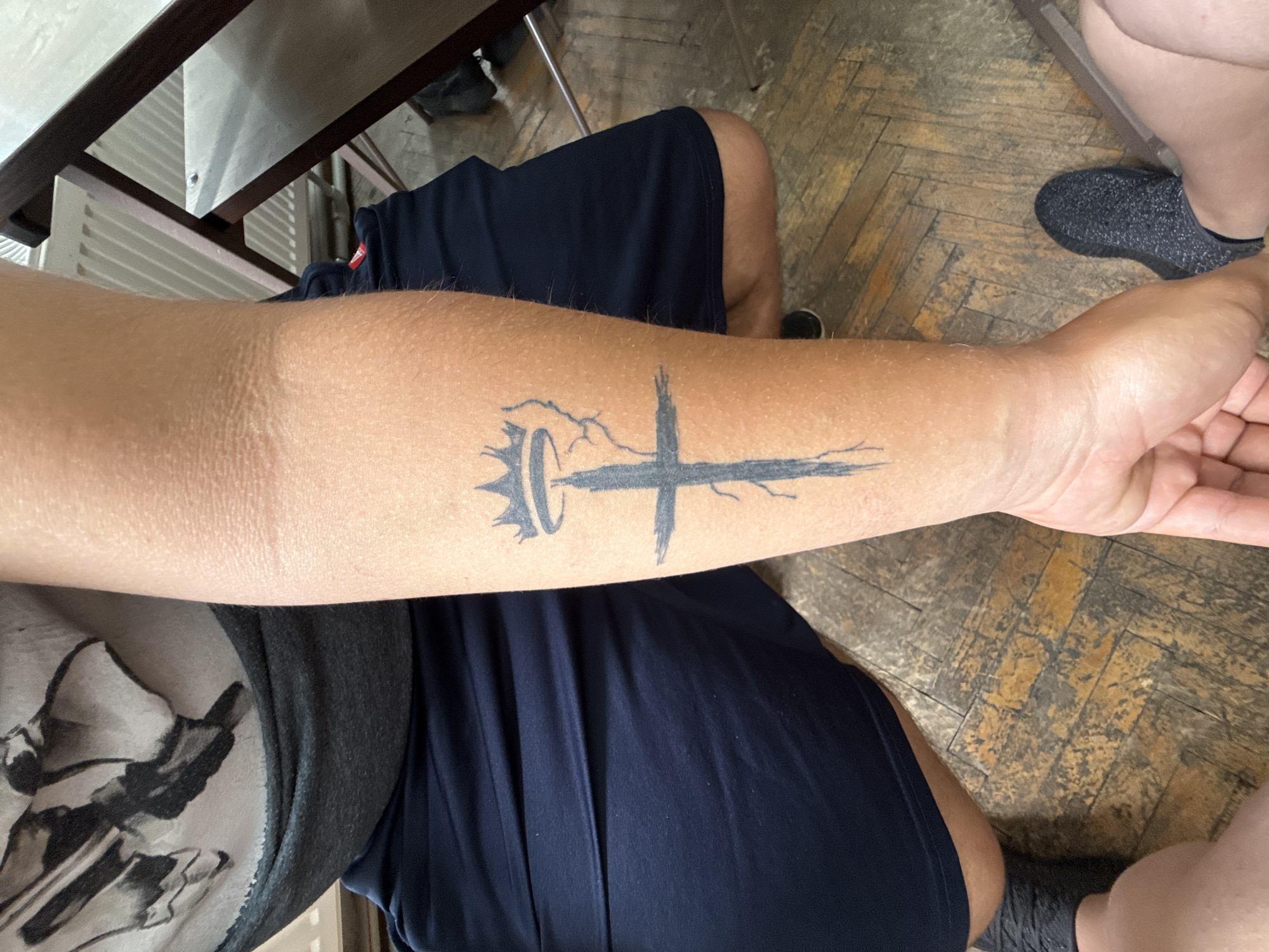 Young man with tattoo writes, uses phone at desk