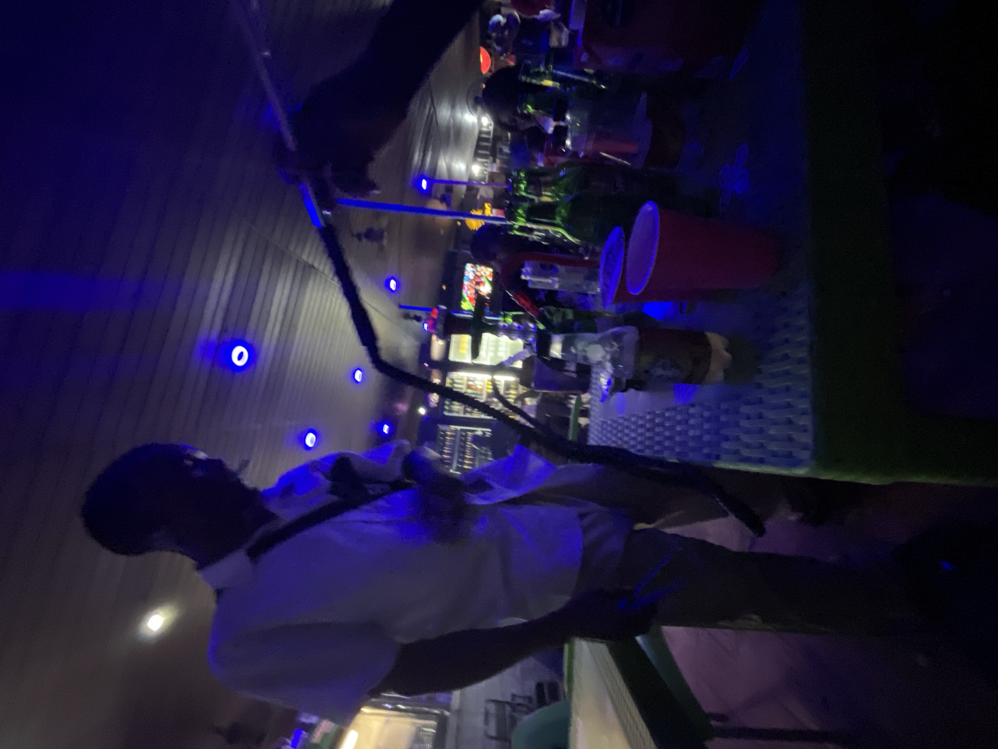 Nigerian youth socialize at blue-lit bars in evening gathering