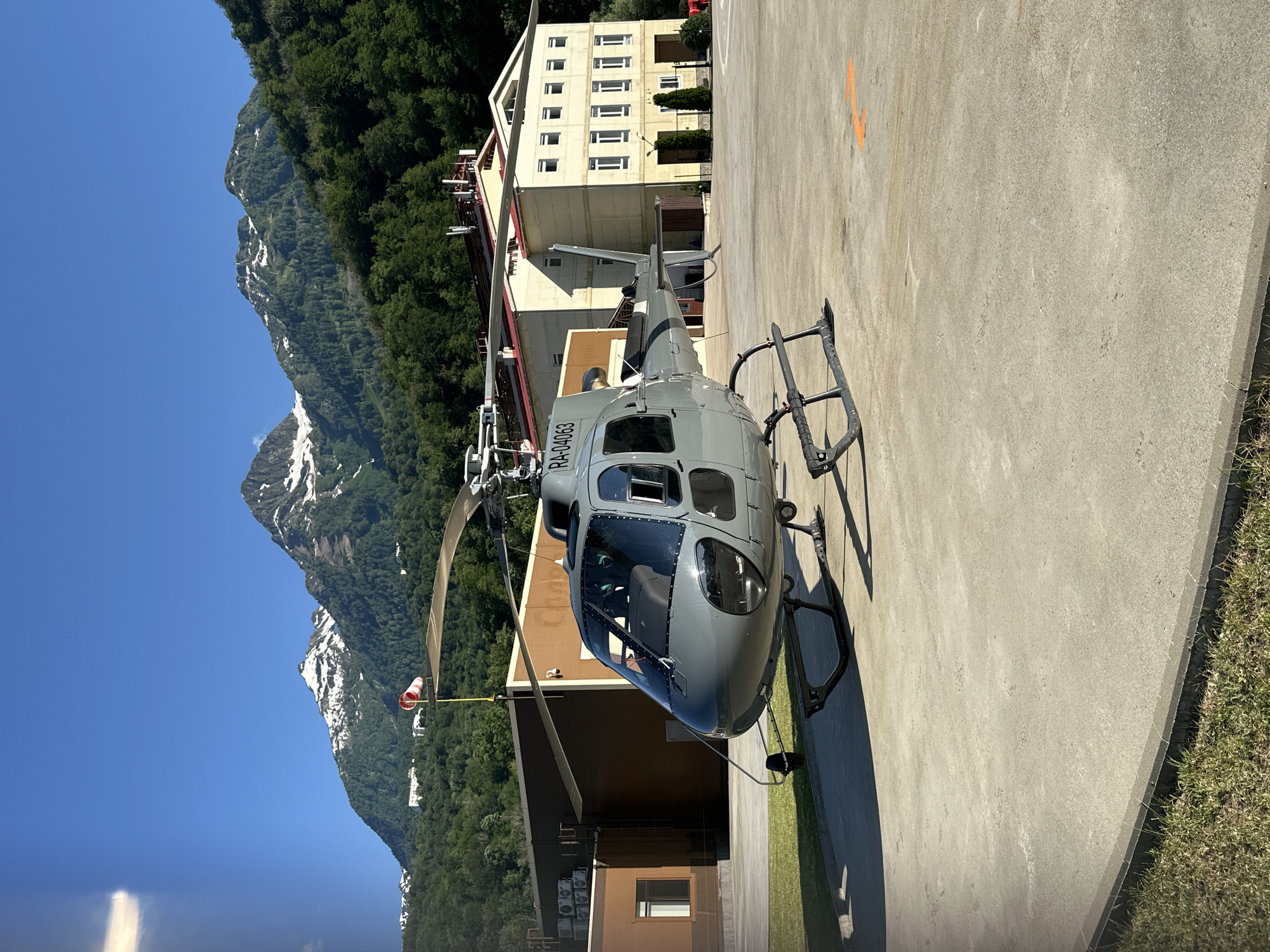 Helicopter parked at Krasnaya Polyana helipad, mountain backdrop
