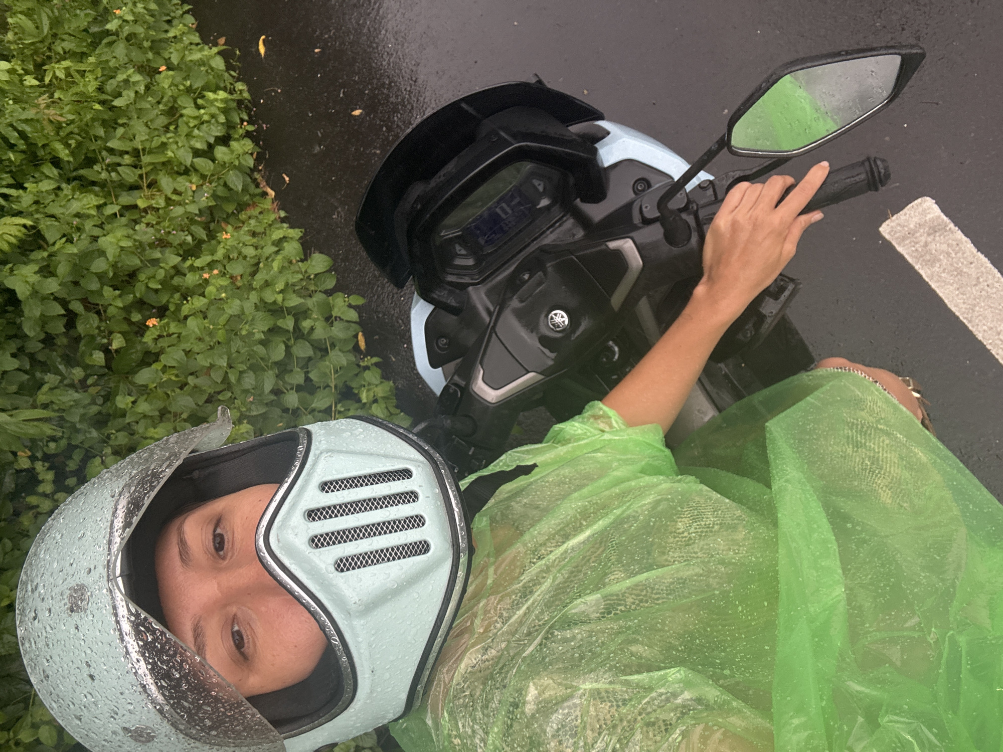 Motorcyclist in raincoat stops roadside in Kuta Selatan