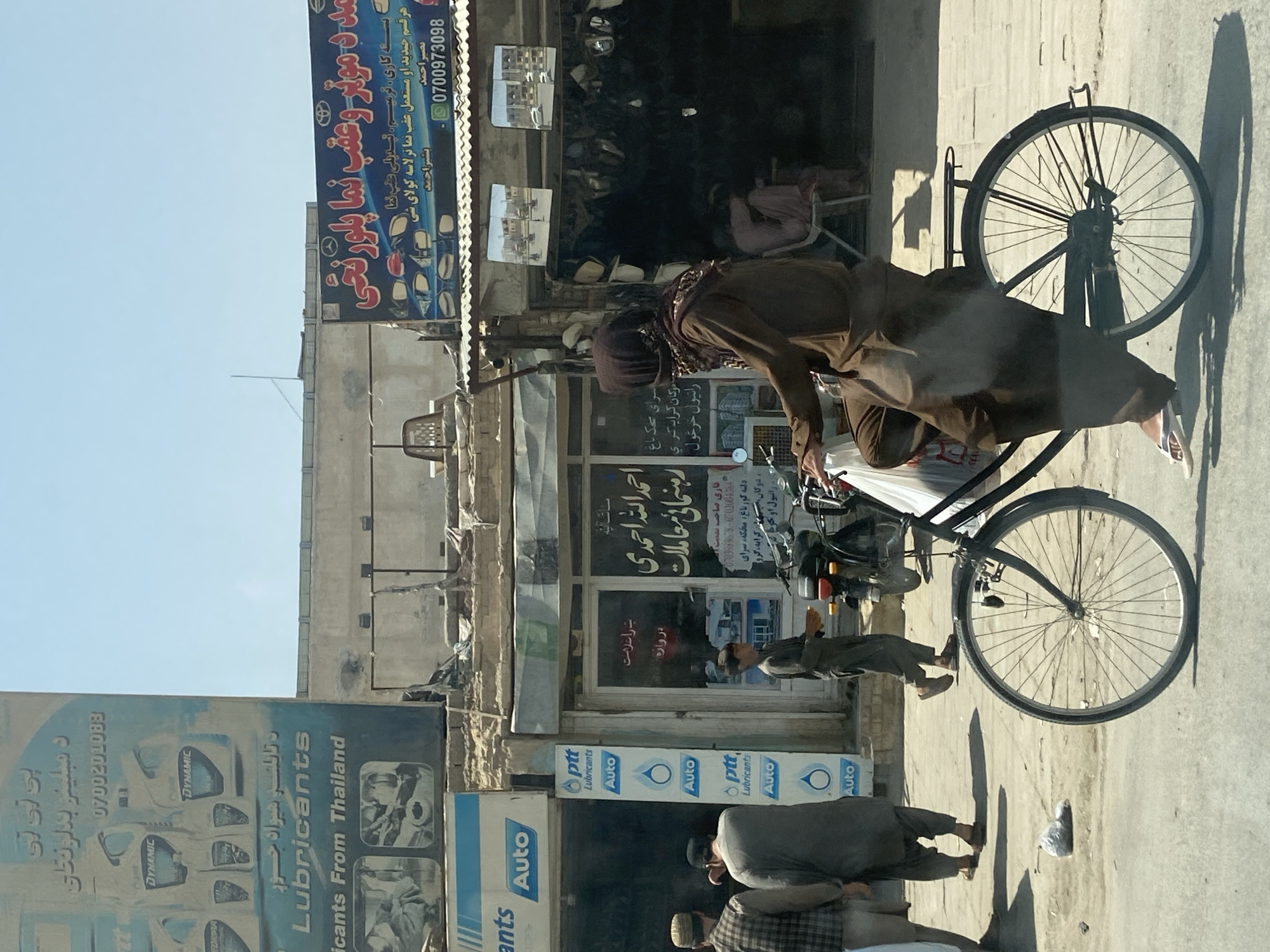 Cycling through Kandahar streets on a mismatched-wheel bicycle