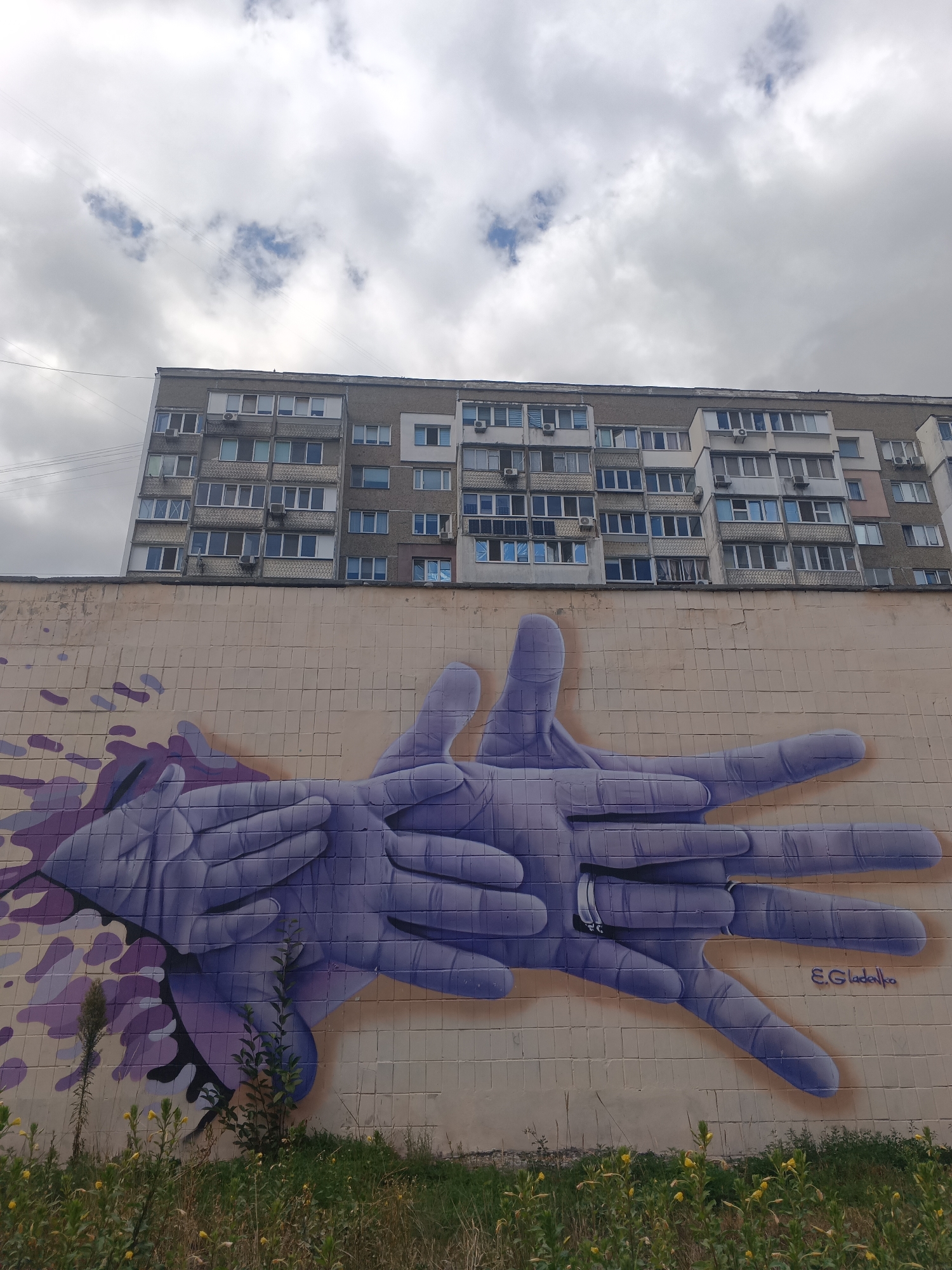 Interlocked purple hands mural on a Kyiv building wall