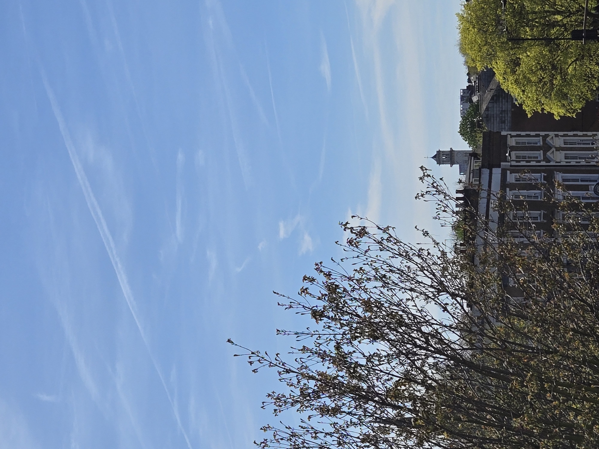 Aircraft contrails cross blue sky over London spring morning