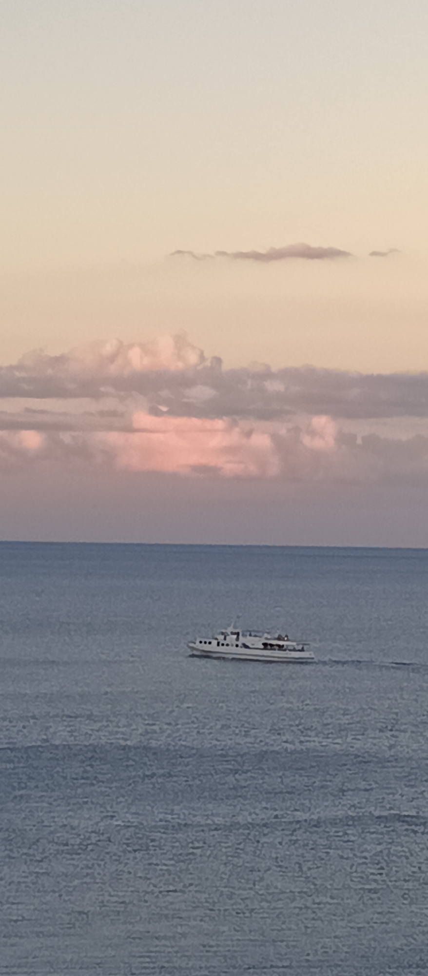 Dusk at a rocky coastal overlook, ferry on calm water