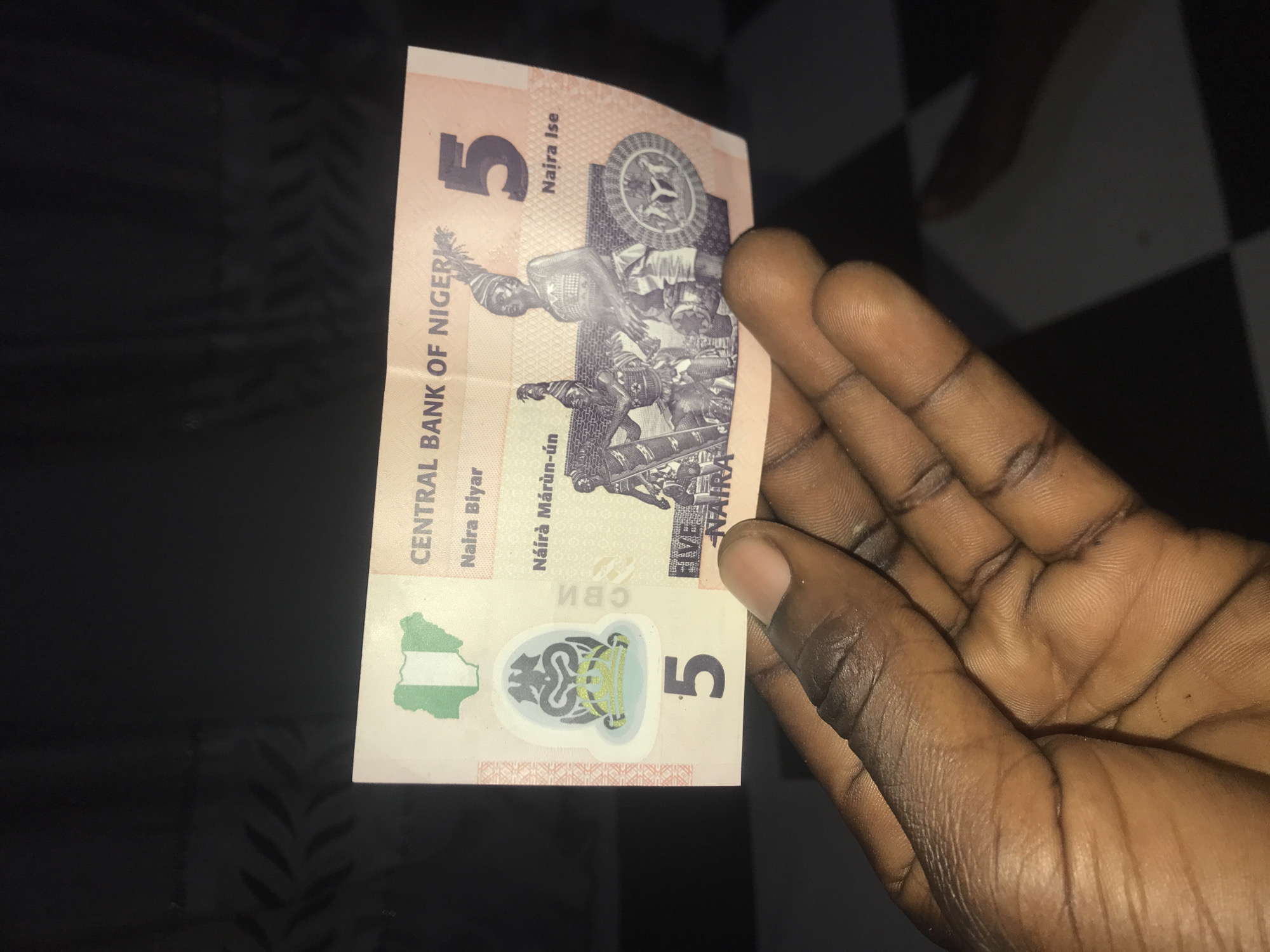 Person holds 5 Naira note and Peak milk on Rukuba Road