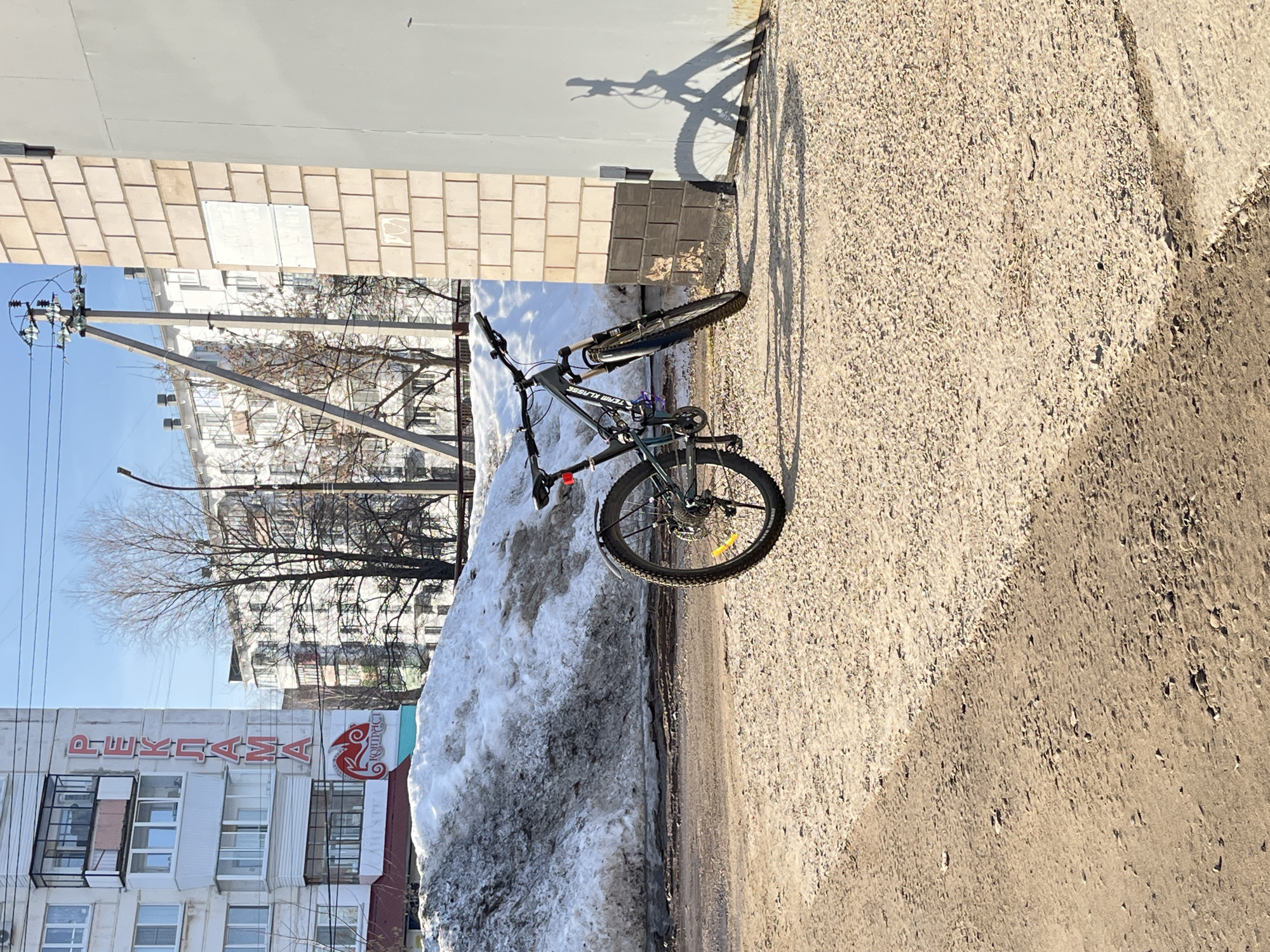 Bicycle parked beside snow pile in Chaikovsky, Russia