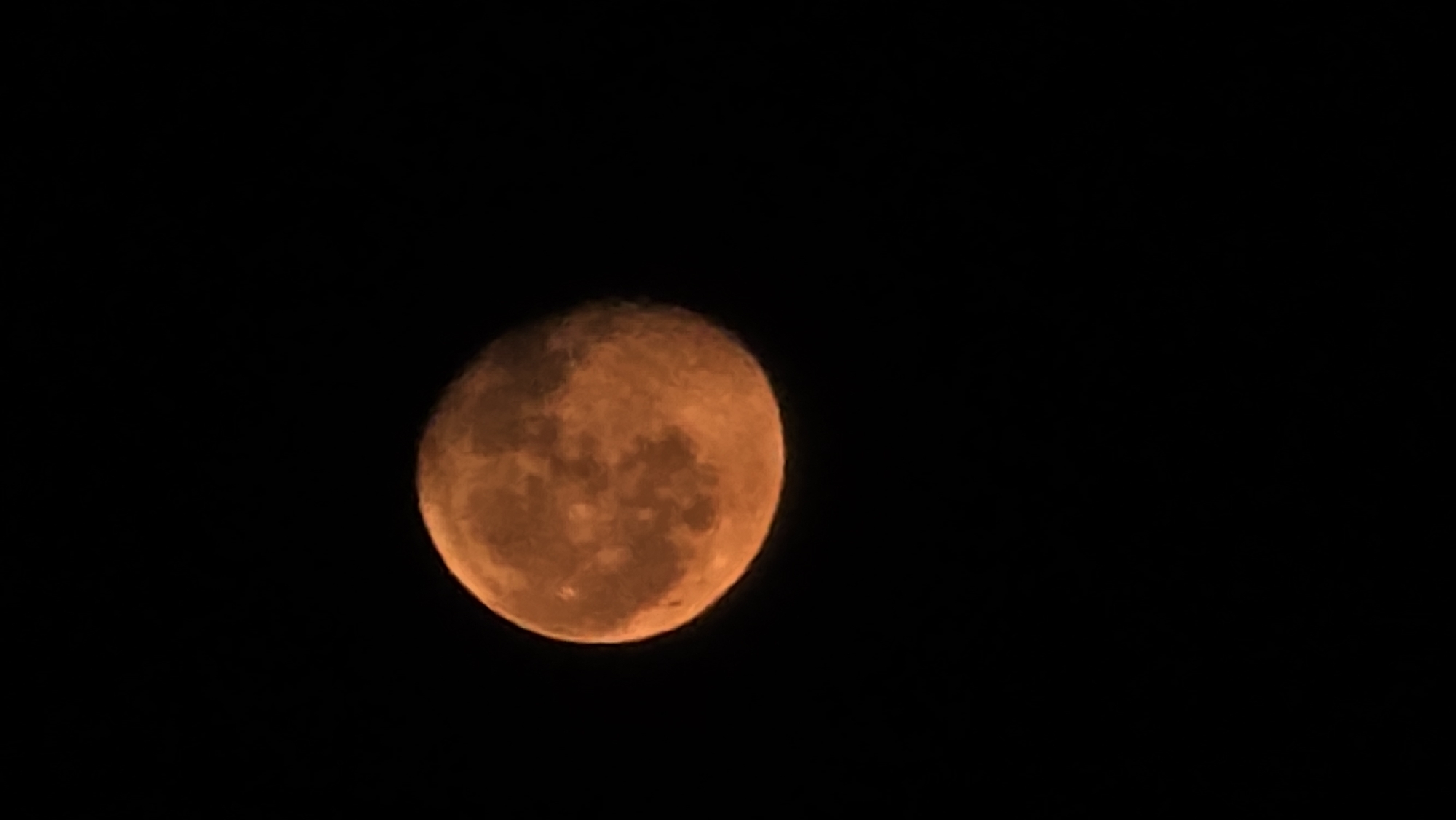 Orange full moon rises over Krasnodar's nighttime skyline