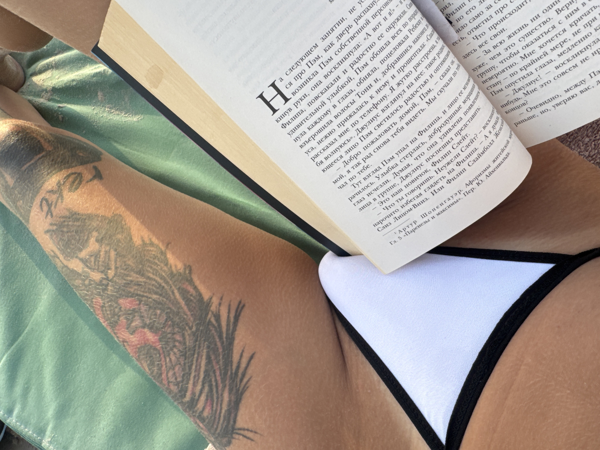 Afternoon beach read, tattoos and Russian book on a lounge chair