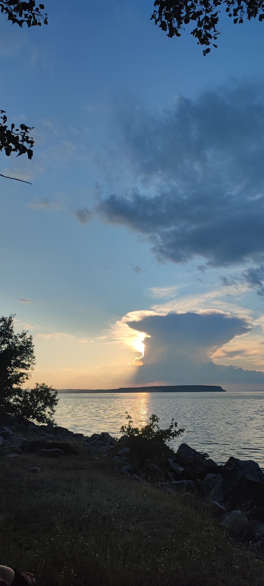 Stormy sunset over the water, picnic on the shore