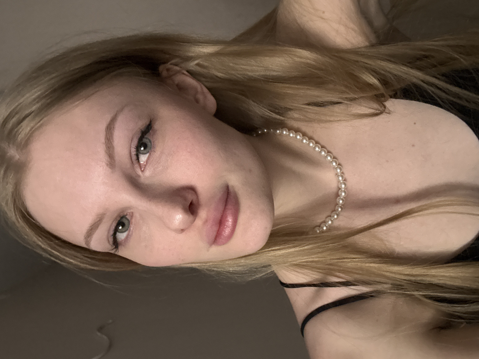 Woman takes selfies in black top, pearls in Perm