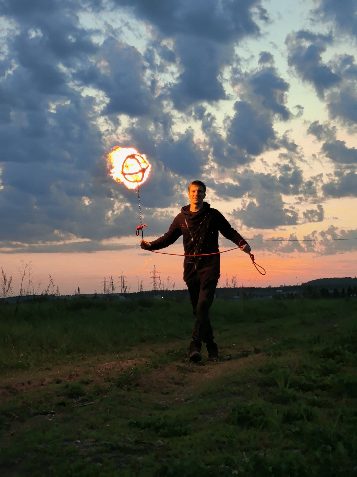 Fire performer spins flaming torches at sunset in Russian field