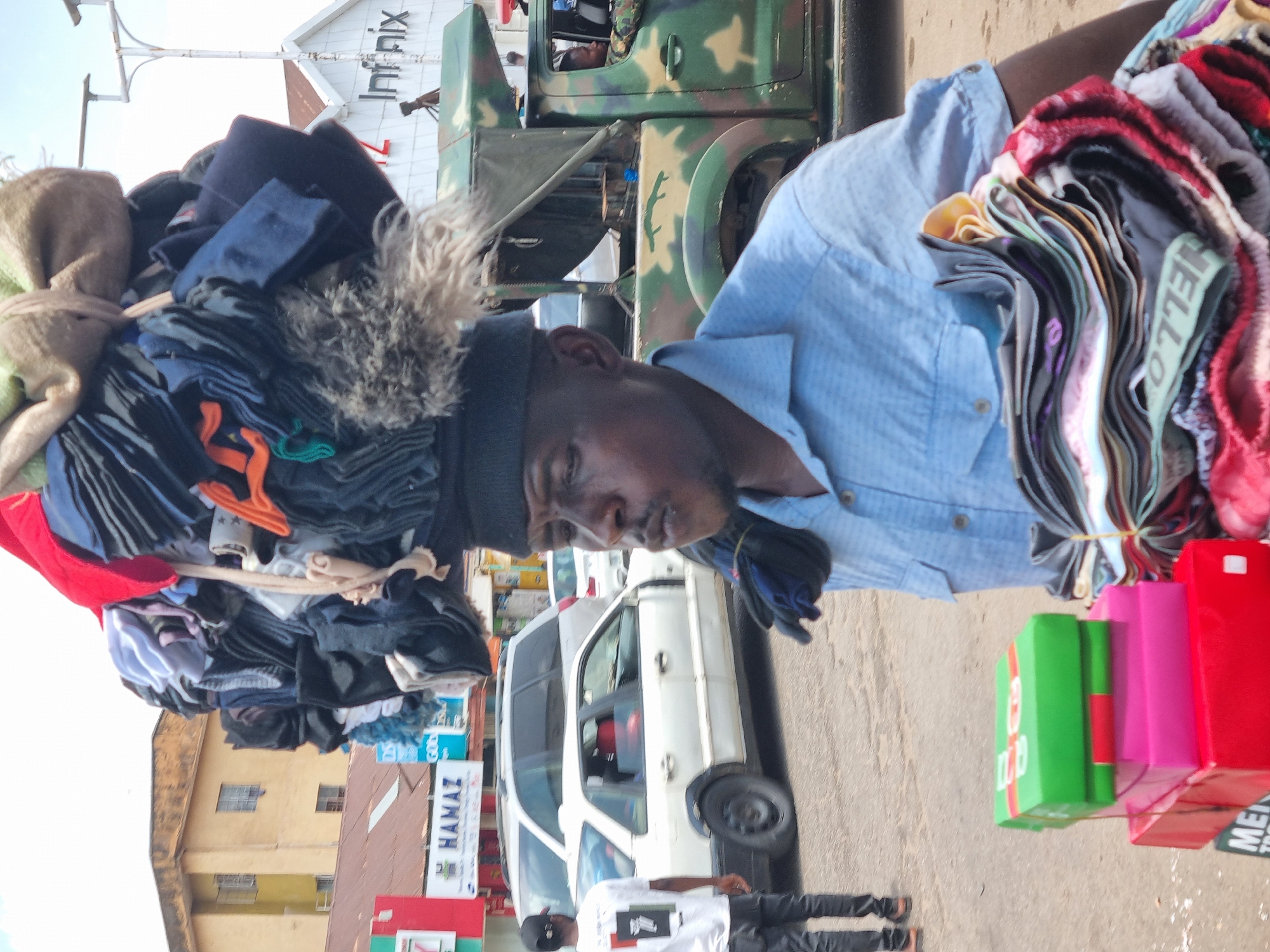 Street vendors carry clothing and kola nuts in Jos