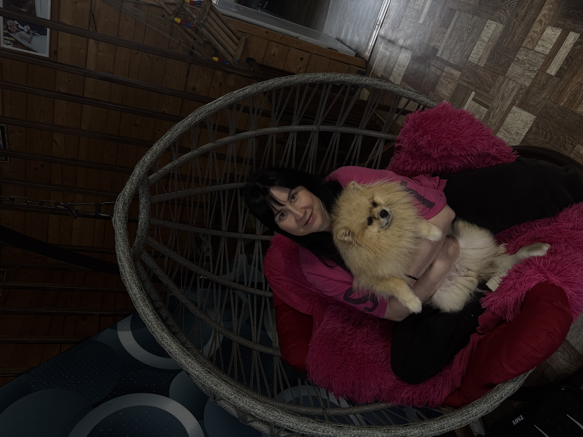 Woman relaxes with Pomeranian in wicker chair, Russia