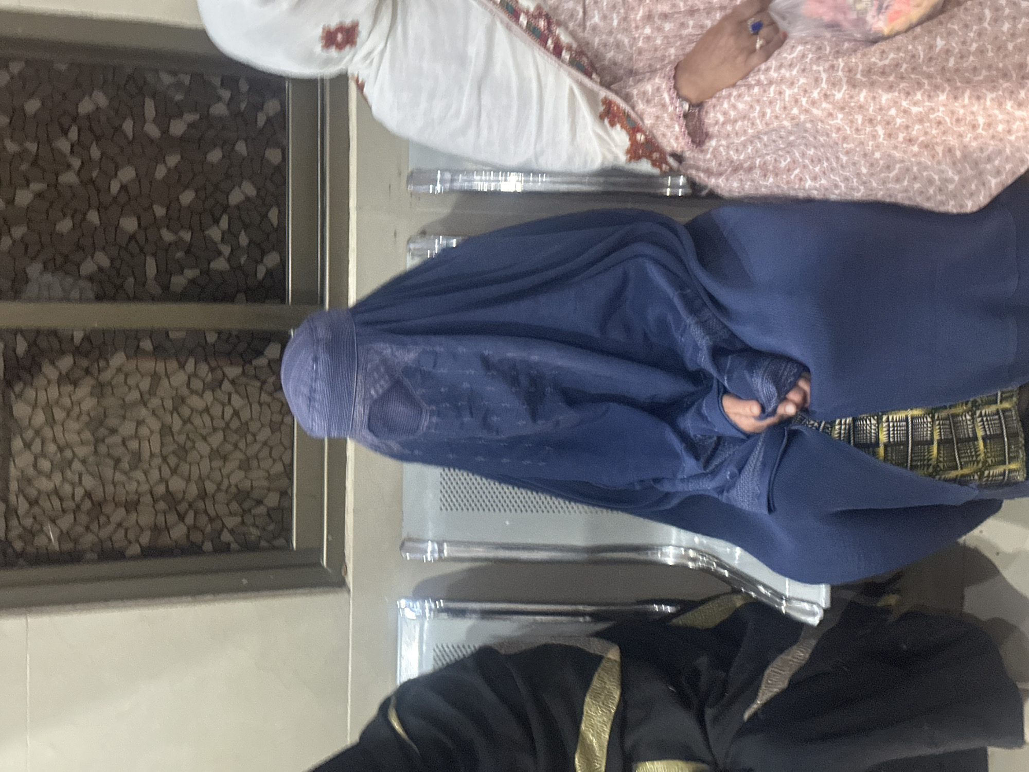 Three people seated together in Quetta, one in full burqa